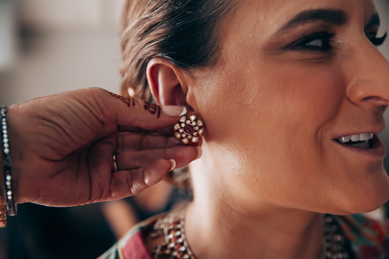 Close-up shot of hand putting on an ornate jeweled earring.