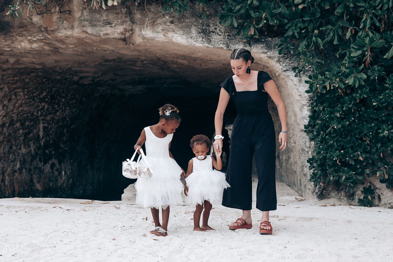 Family members in formal wear stand together in front of a stone cave entrance.
