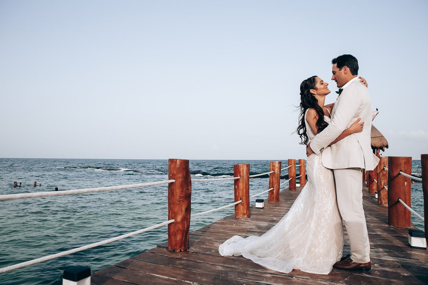 Romantic wedding photos on a wooden pier overlooking the ocean at sunset.
