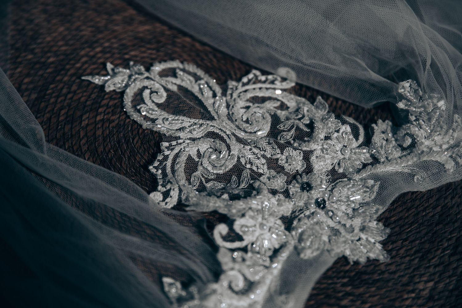 Detailed macro shot of intricate lace embroidery on white wedding veil.