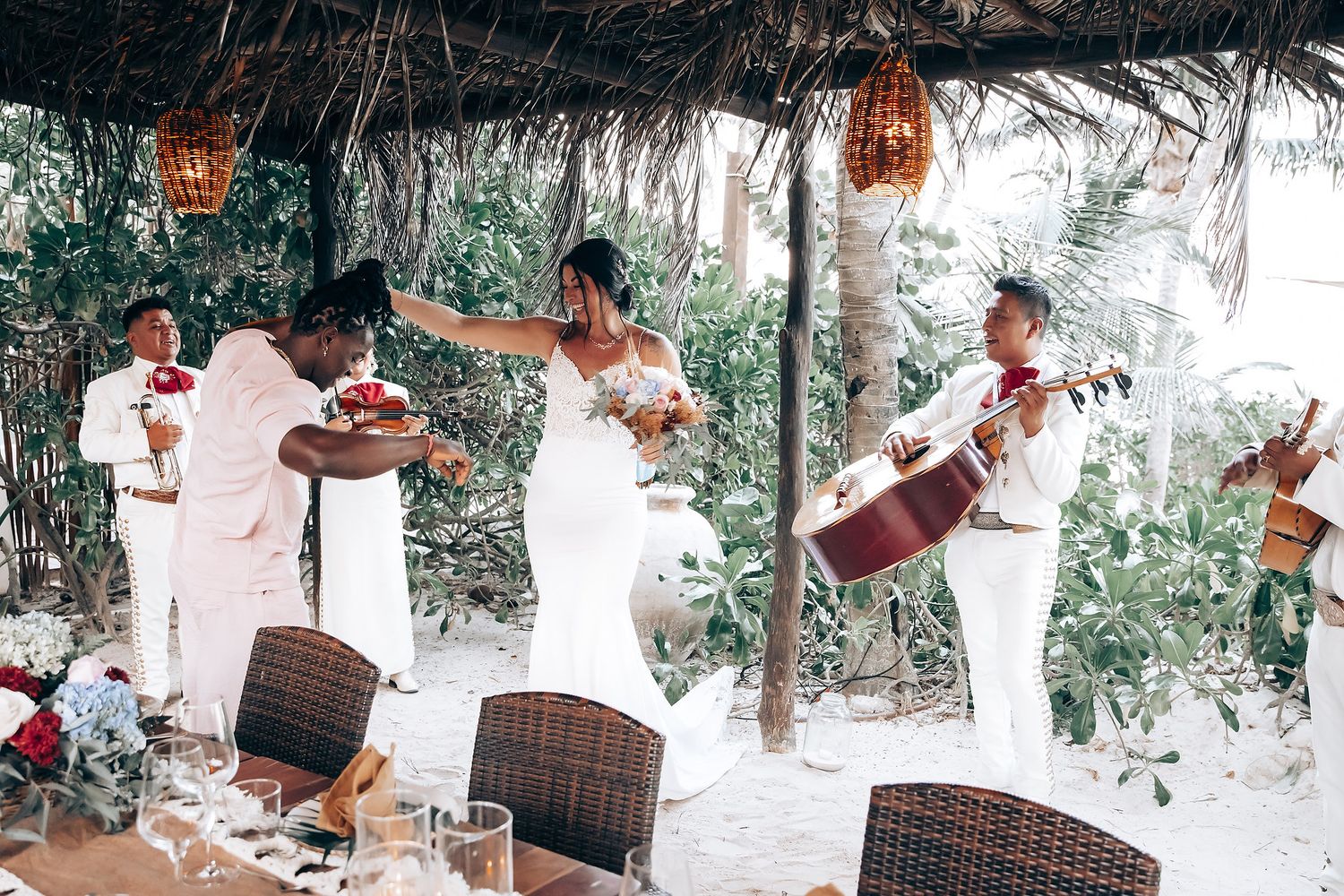 The image shows a bride and groom walking together on a beach, with the bride's dress flowing in the wind.