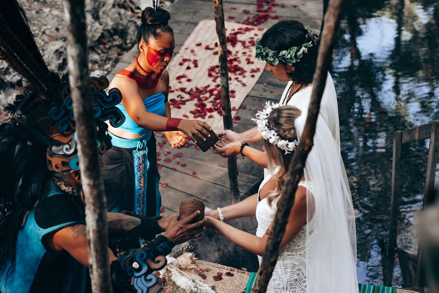 Couple in wedding attire sharing a tender moment in a forest setting with sunlight filtering through trees.