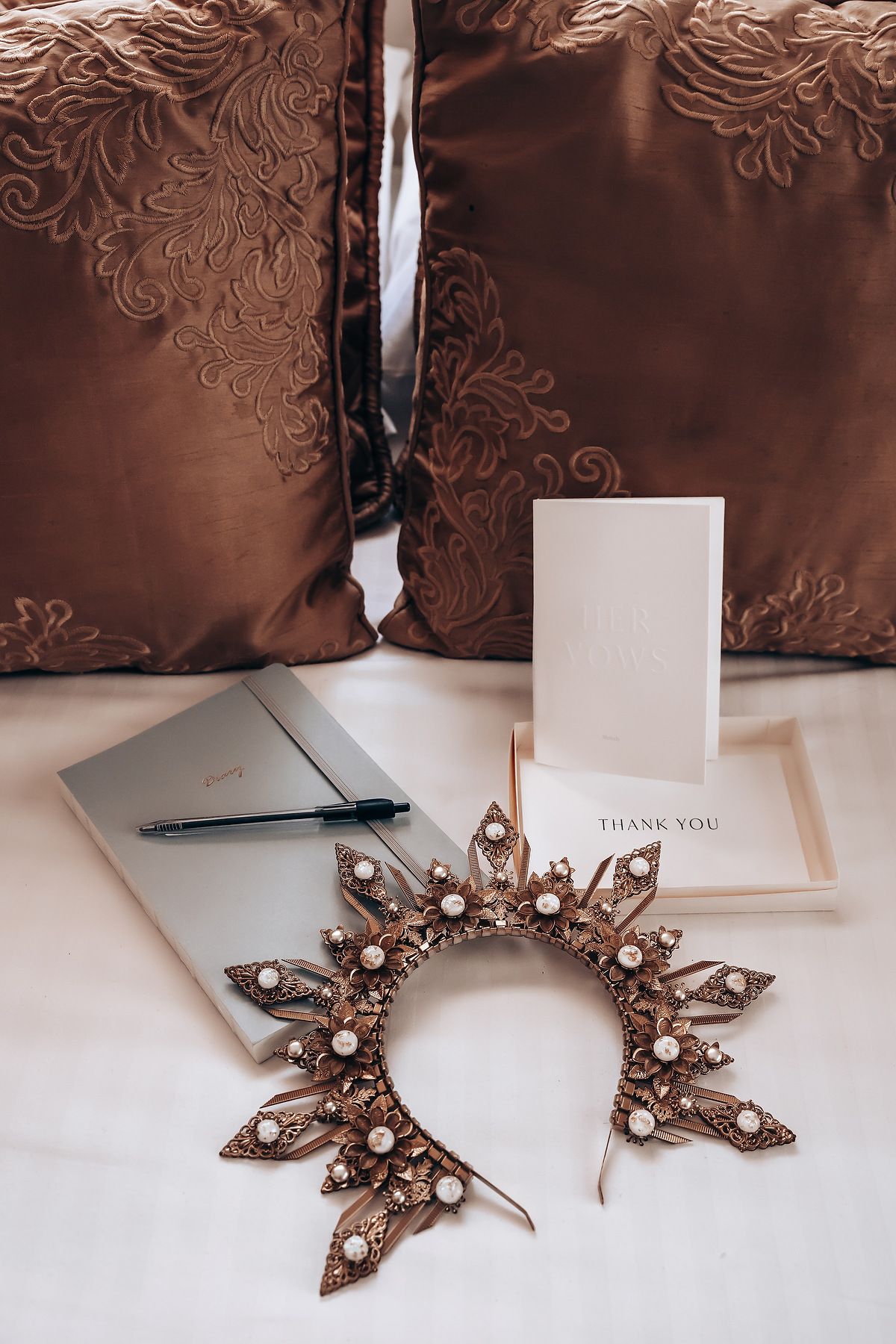 Elegant vintage-style brooch with pearls and crystals displayed against white paper and brown fabric background.