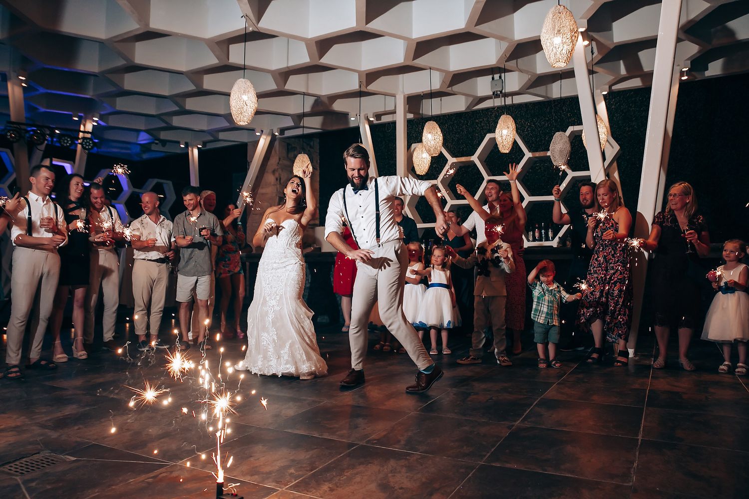 Wedding reception dance floor illuminated with string lights as guests celebrate in the evening.