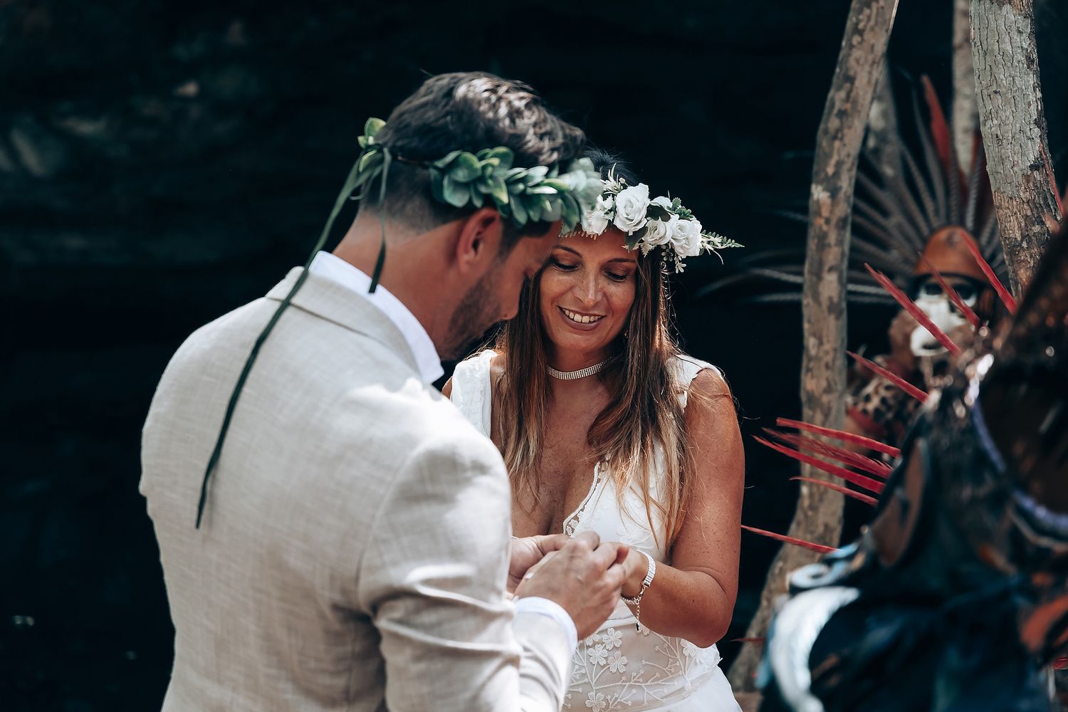 Intimate wedding ceremony moment in a forest with spiritual elements and white floral details.