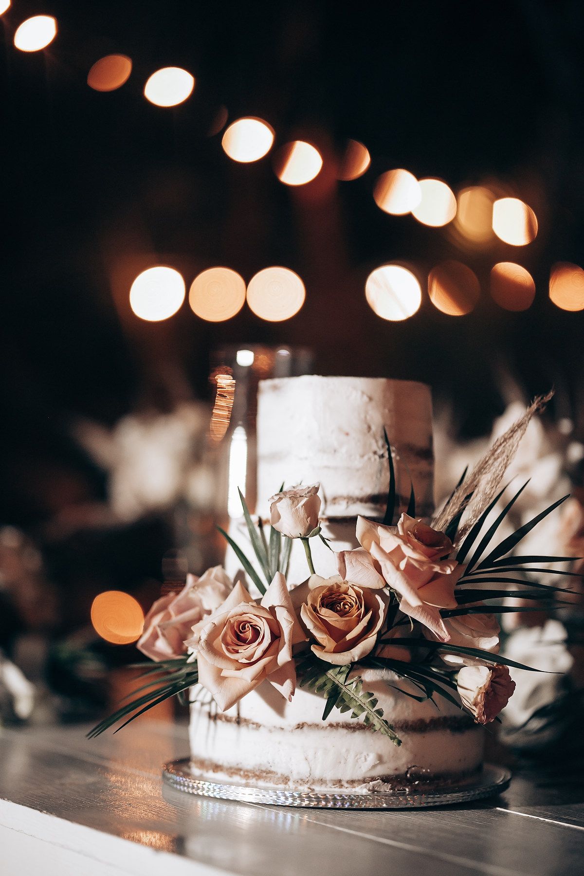 Elegant rose gold roses and pearl decorations arranged on a reflective surface with bokeh lights in the background.