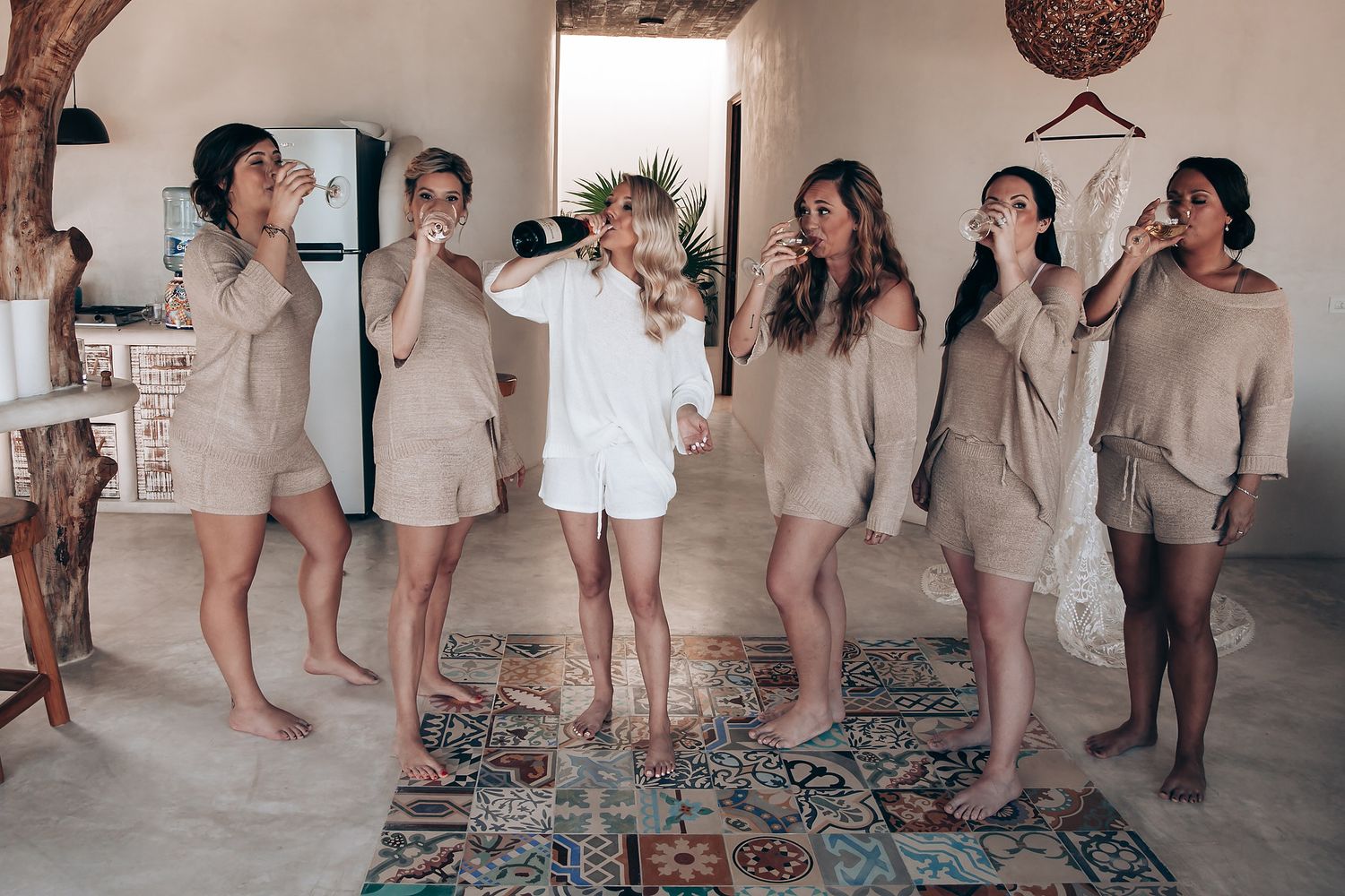 Group of people in casual white outfits dancing and having fun in a bright indoor space.