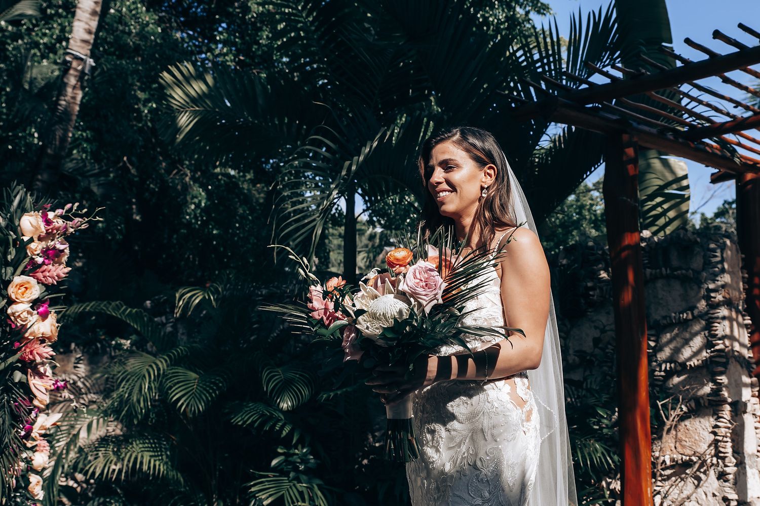 Wedding scene in tropical garden with floral arrangements and palm trees.