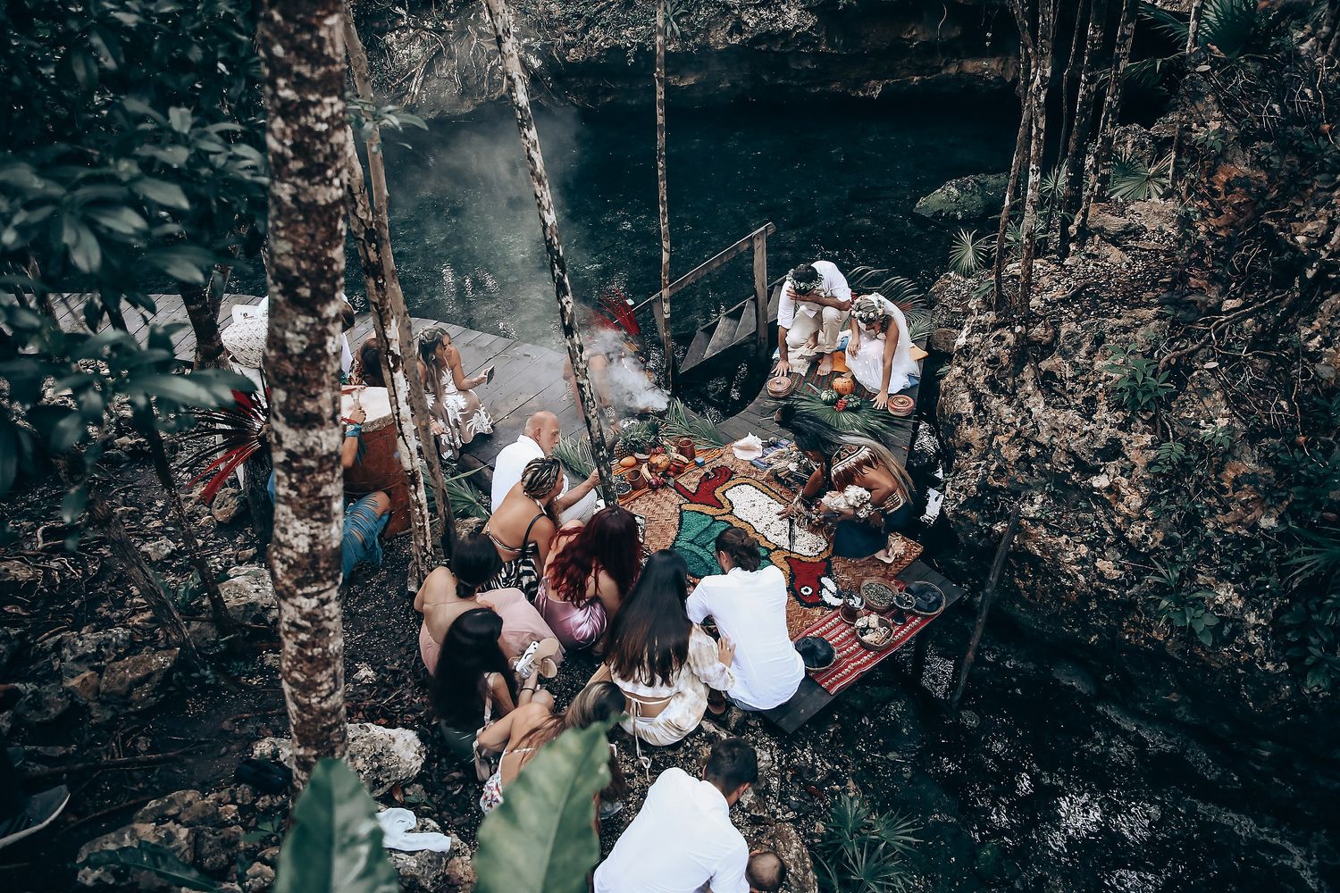 An aerial view of a forest wedding ceremony with guests gathered in a natural setting.