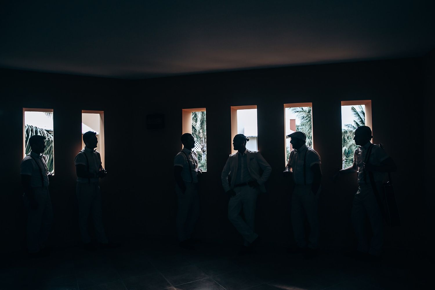 Silhouettes of people standing in front of bright windows in a dark room.