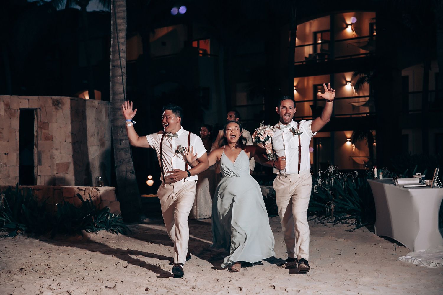 Wedding reception party on beach at night with ambient lighting and dancing.