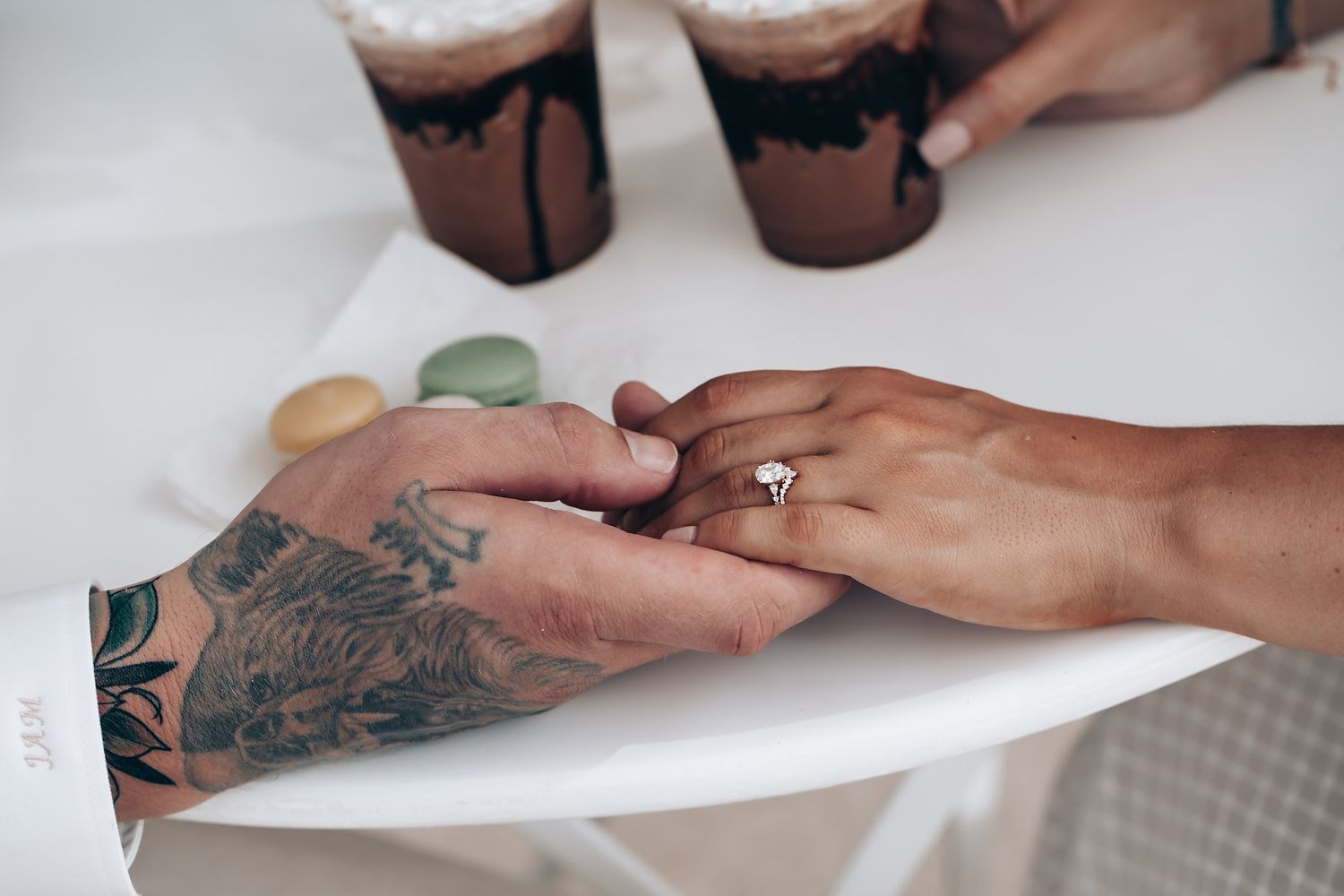 Close-up of tattooed hands exchanging rings during wedding ceremony.