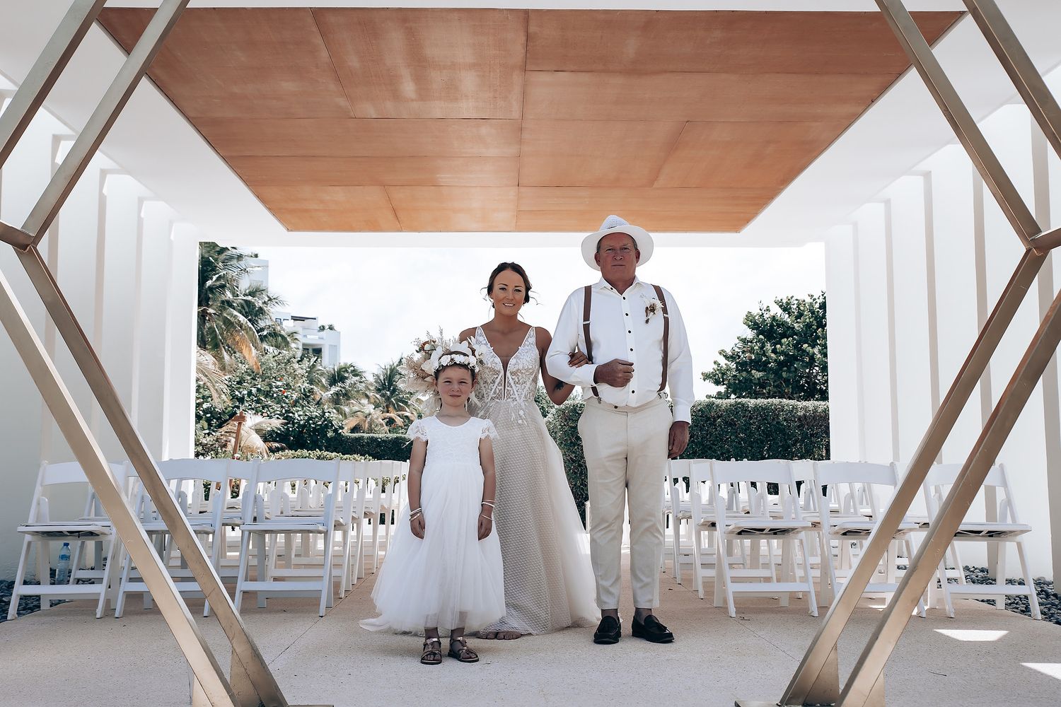 A wedding ceremony setup with white chairs and decorative elements under a covered outdoor venue.
