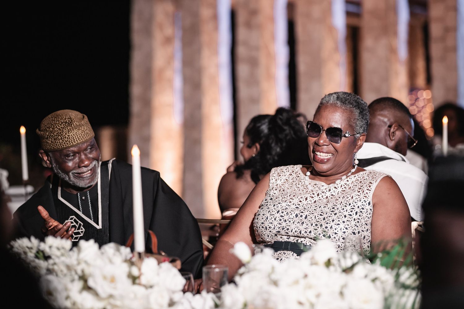 Two elegantly dressed wedding guests laughing and enjoying the reception dinner celebration.