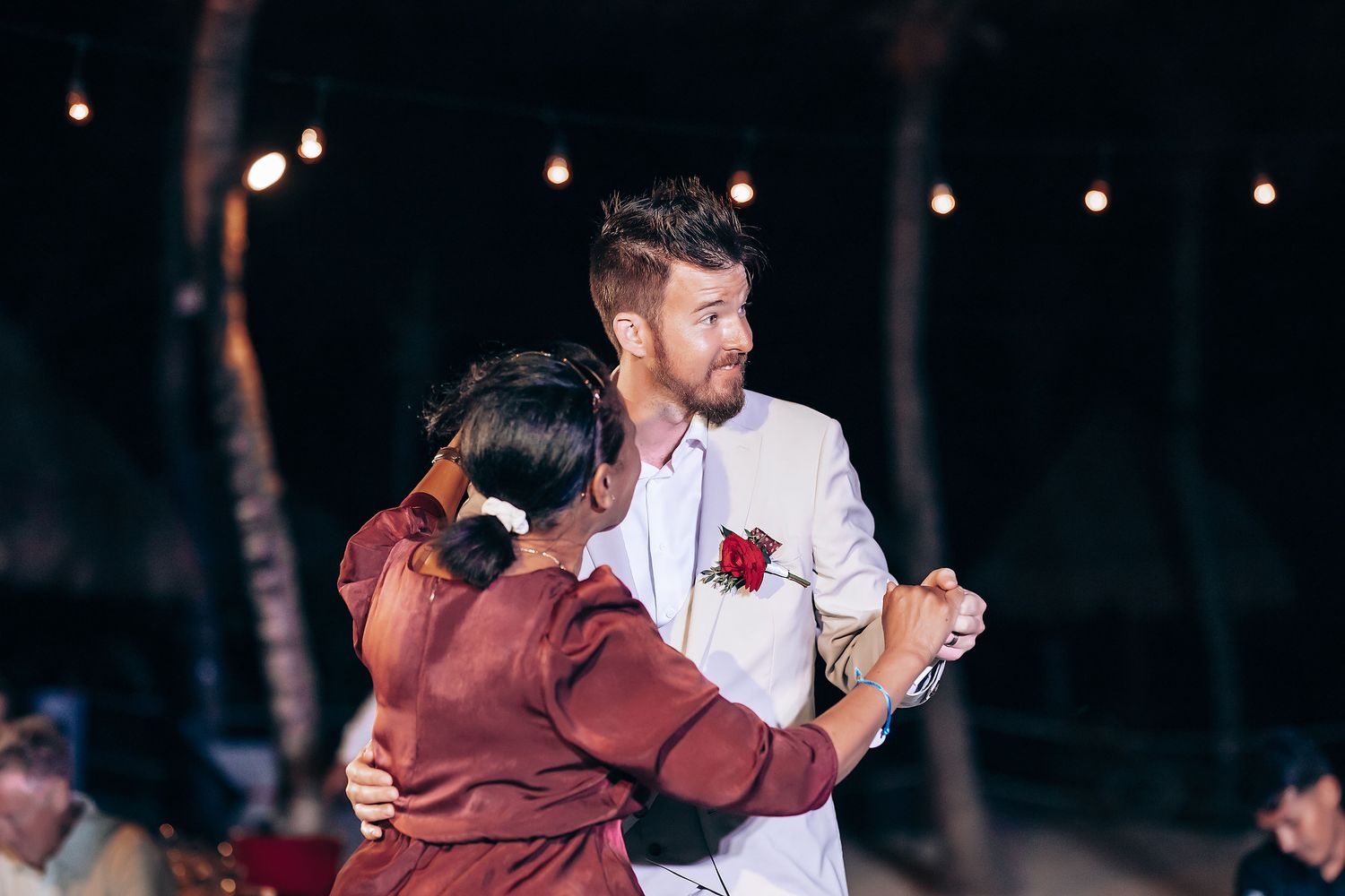 Couples dancing together at a nighttime wedding reception with ambient lighting.