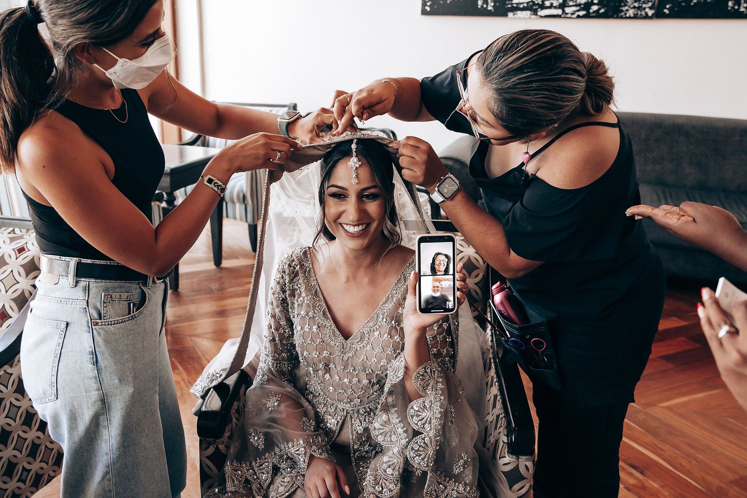 Wedding preparation scene showing hands helping with final bridal styling touches.