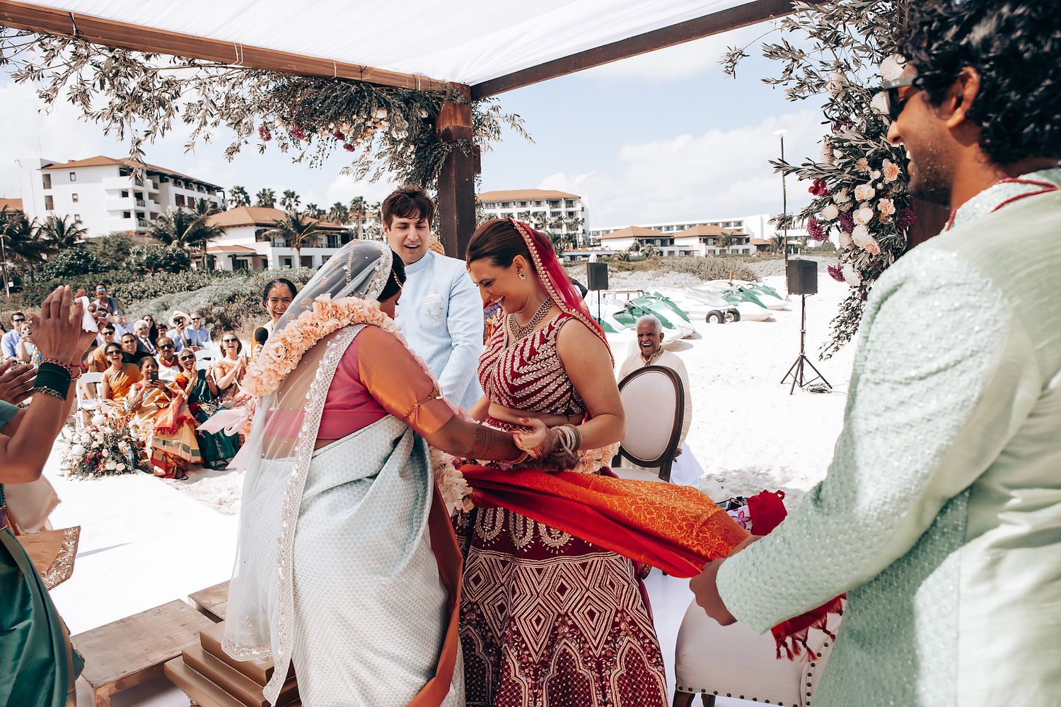 Candid moments from a beach wedding ceremony showing guests in traditional Indian attire.