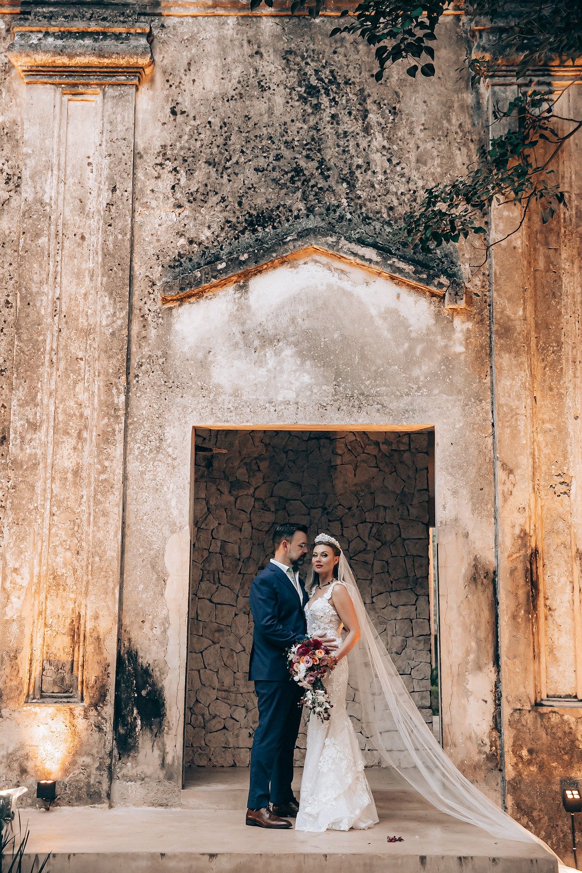 Wedding ceremony in historic stone venue with dramatic lighting and architecture.