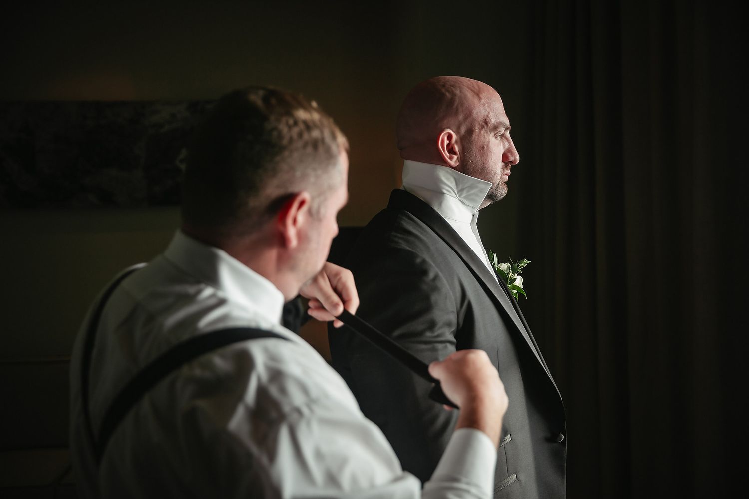 Figures in suits are captured in dramatic lighting against a dark interior space.