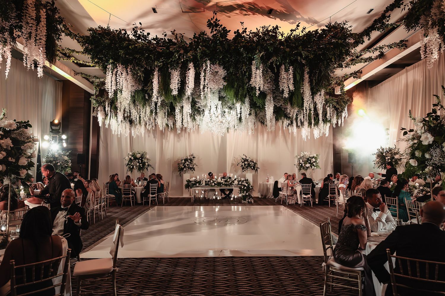 A wedding reception venue decorated with elegant greenery and string lights creating a romantic indoor garden atmosphere.