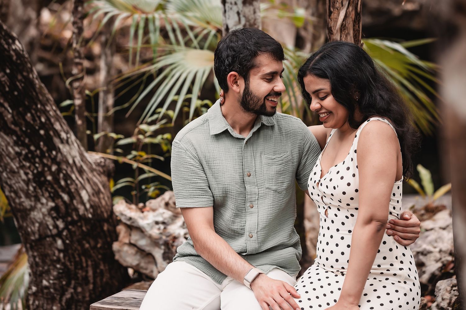 Romantic couple shares tender moments in a tropical garden setting with palm trees and natural lighting.