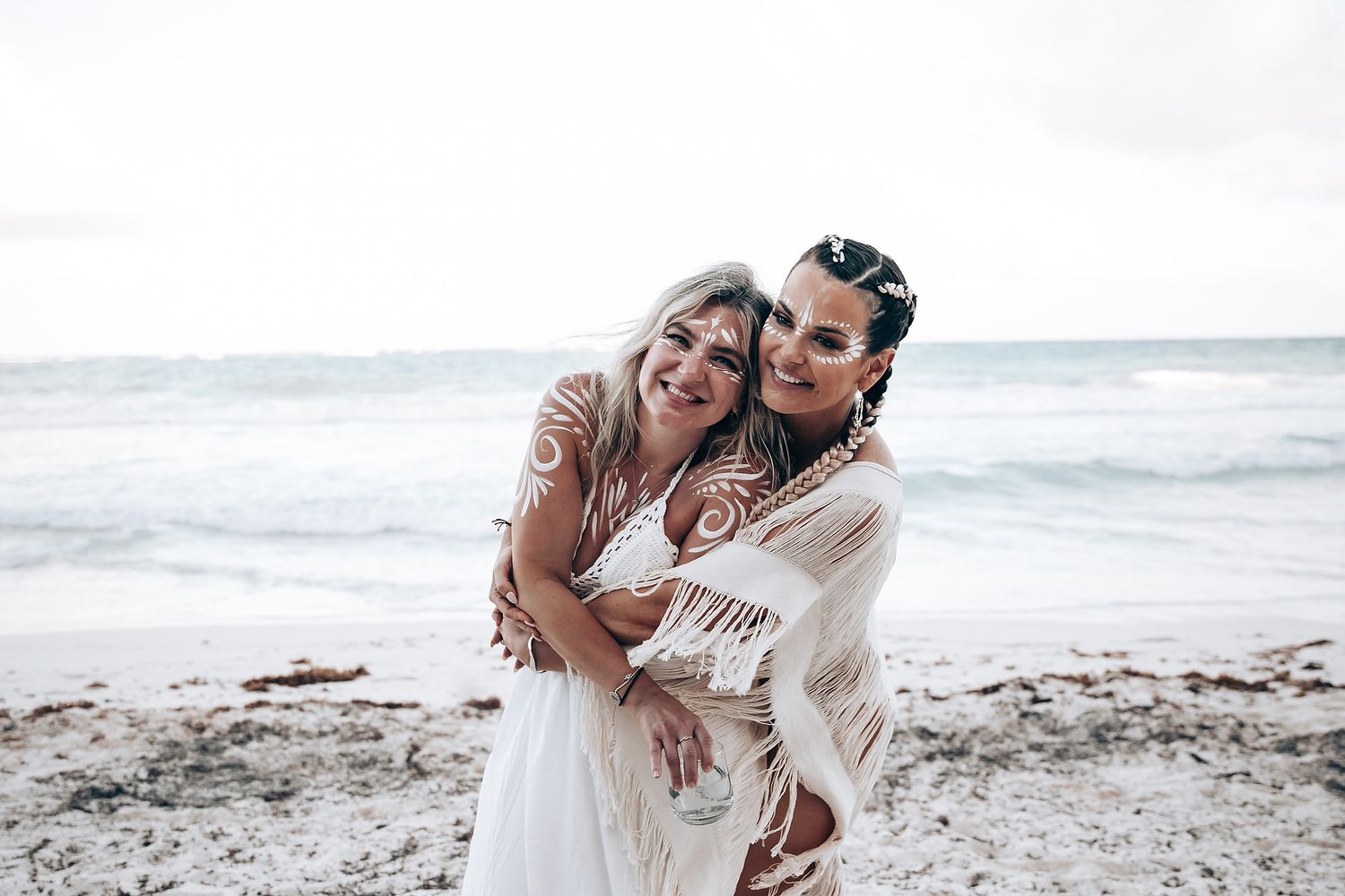 A joyful embrace captured on a cloudy beach with waves in the background.