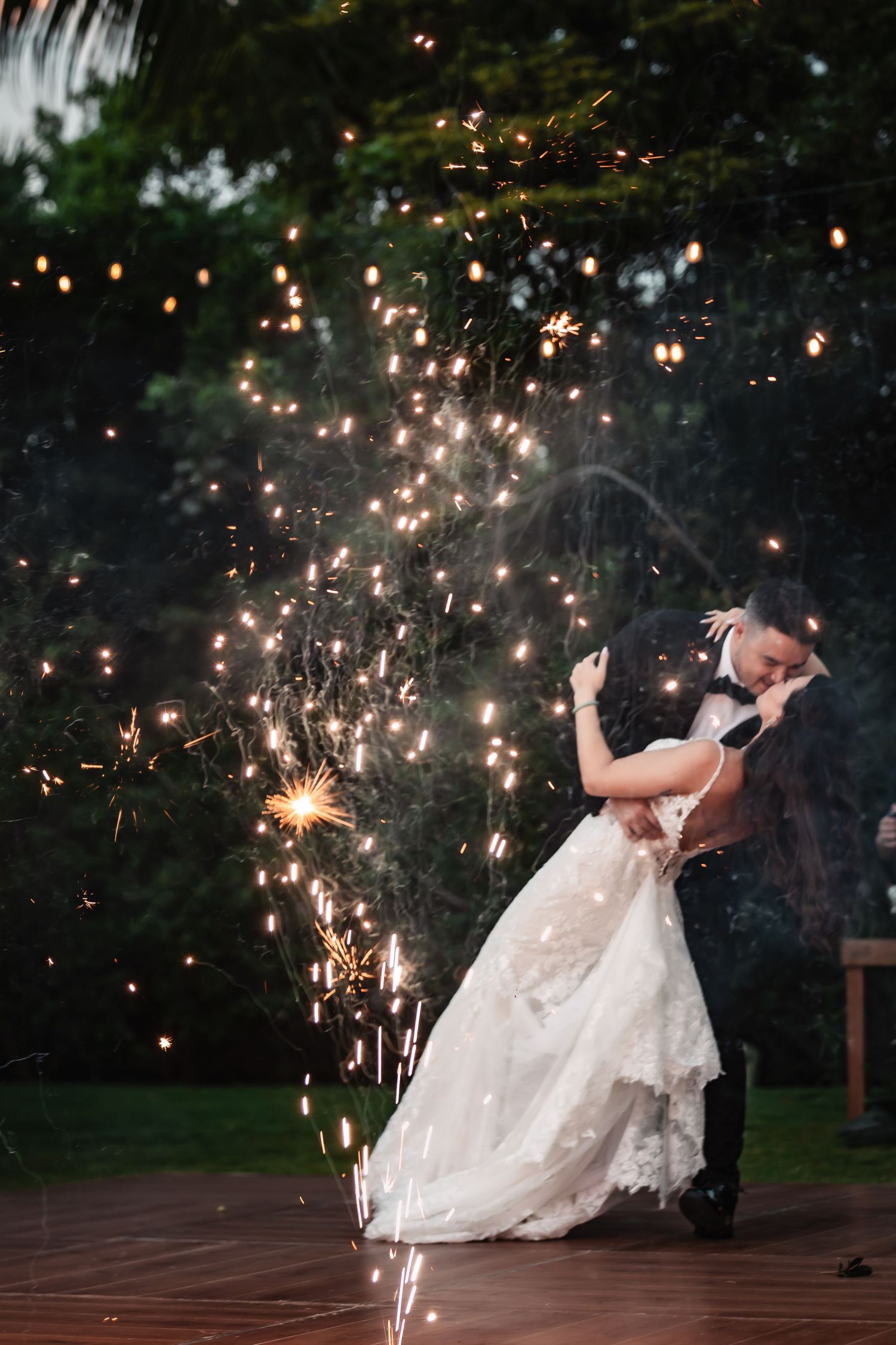 Romantic sparkler dance moment during an outdoor evening wedding celebration.