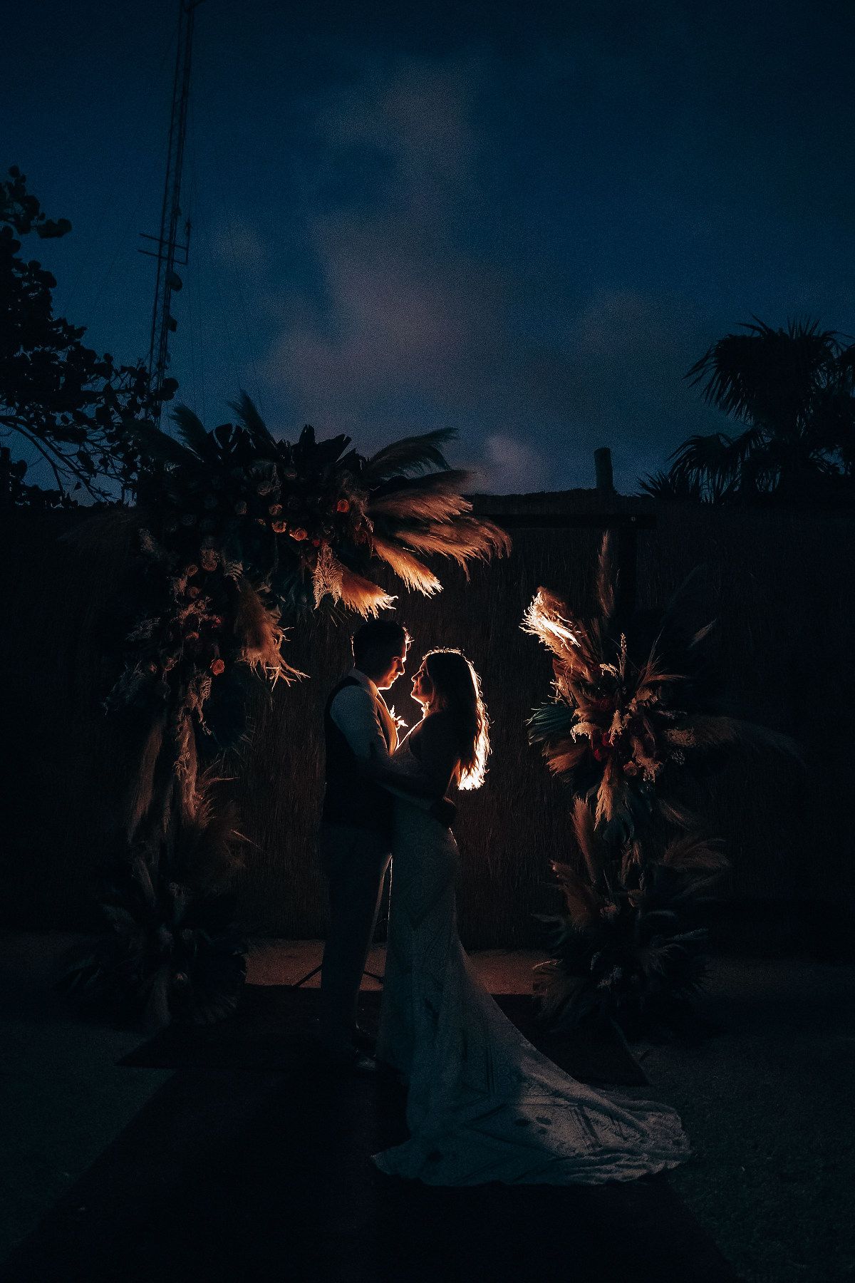 Moody evening wedding photography with torch lighting and tropical garden scenery.