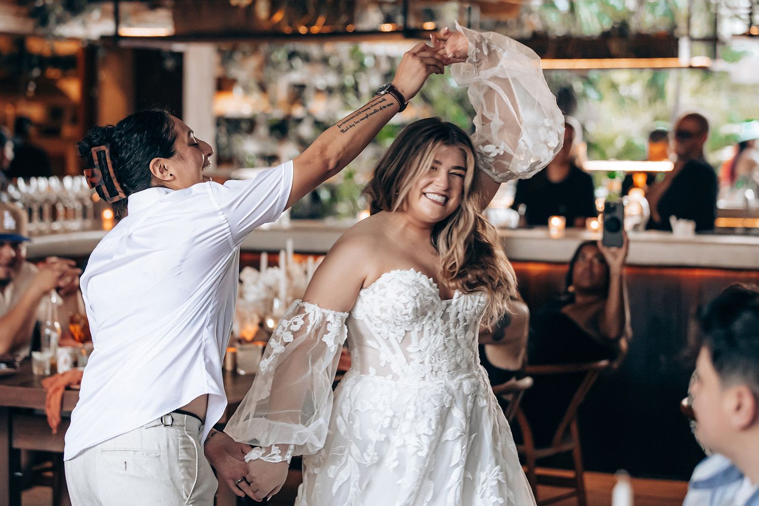 Wedding guests dance and celebrate on an illuminated dance floor during a joyful reception celebration.