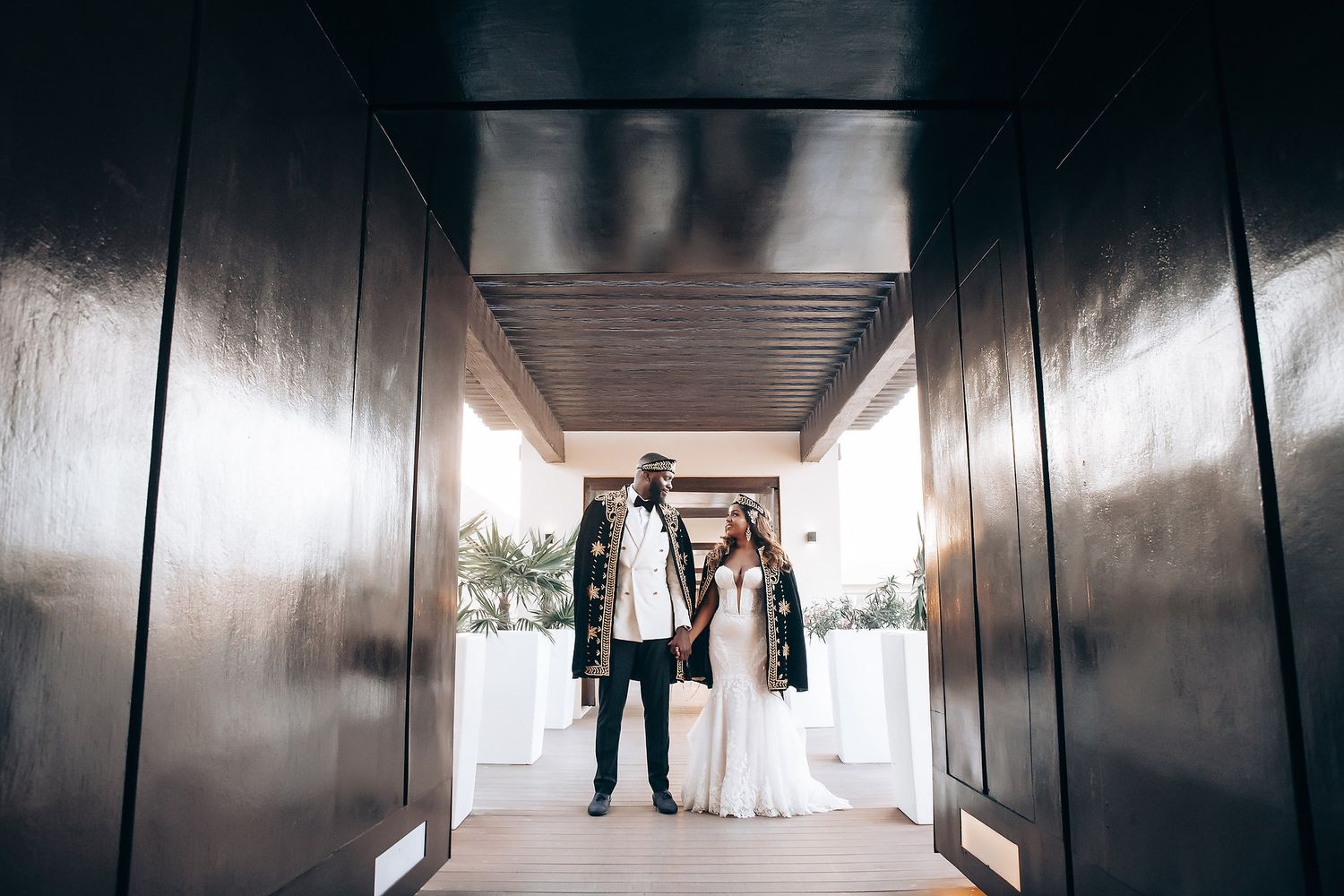 Dark hallway with dramatic lighting showing silhouettes in formal wedding attire.