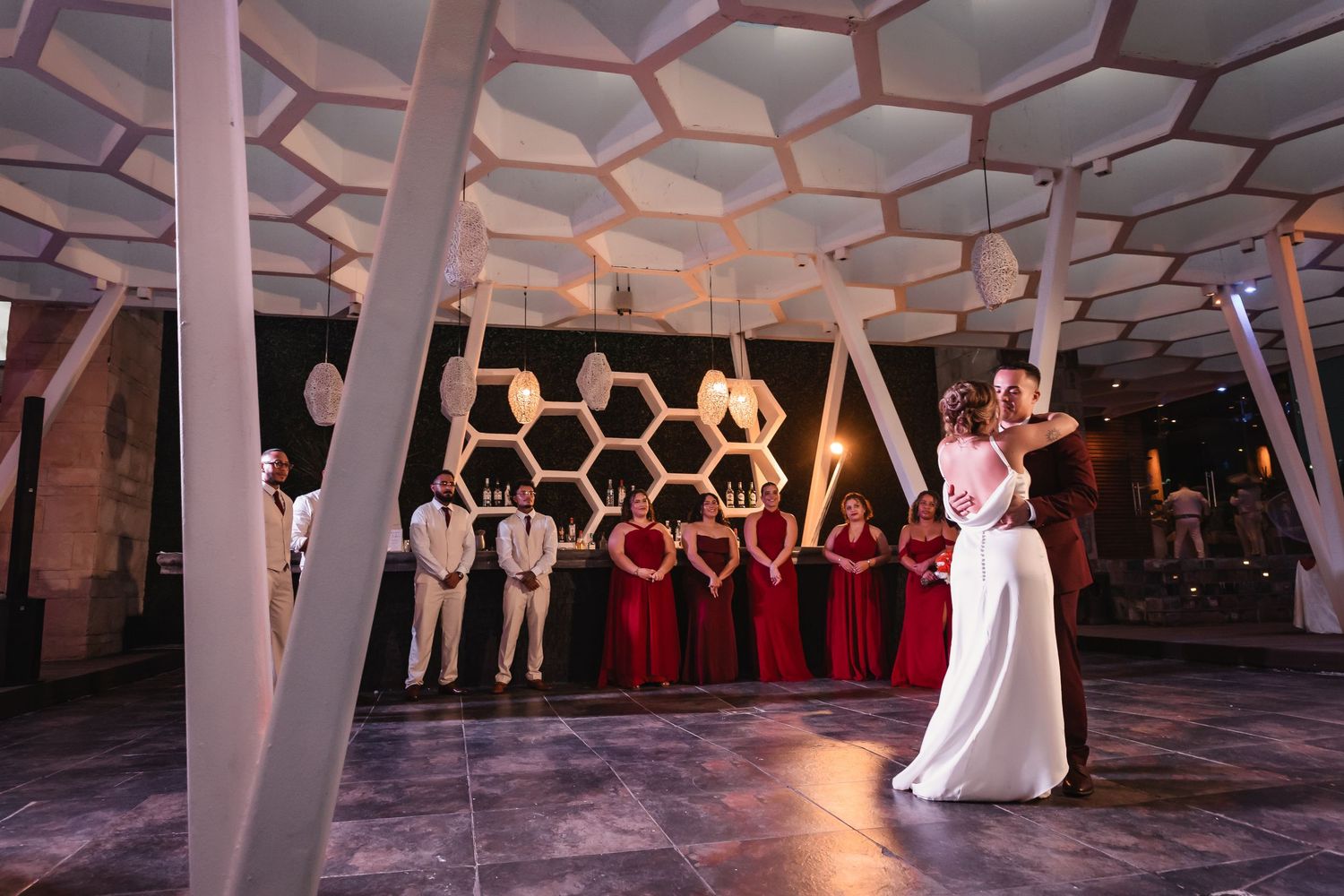 Modern reception venue featuring hexagonal ceiling design and dramatic lighting.