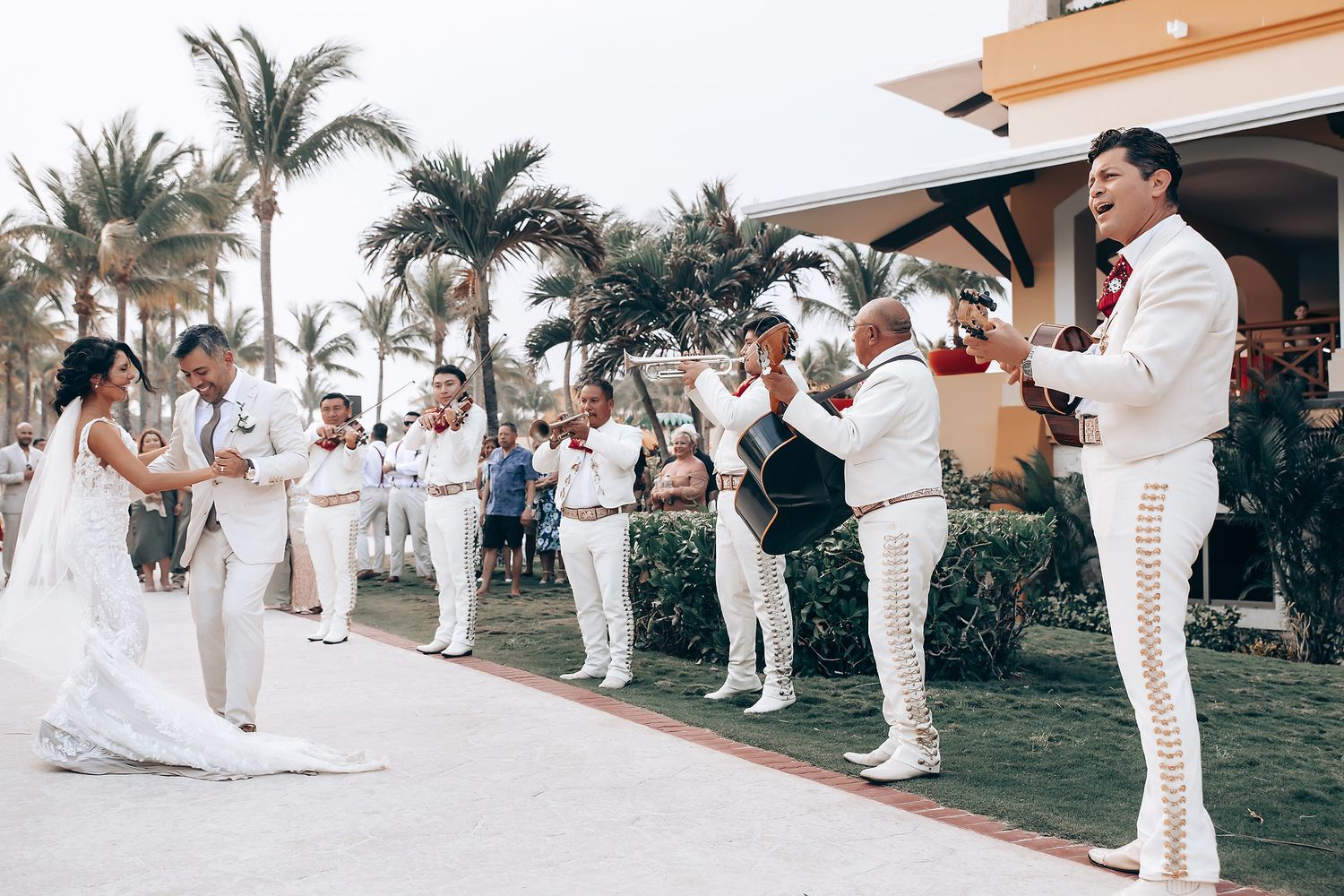 Wedding celebration with mariachi band performing on tropical resort grounds.