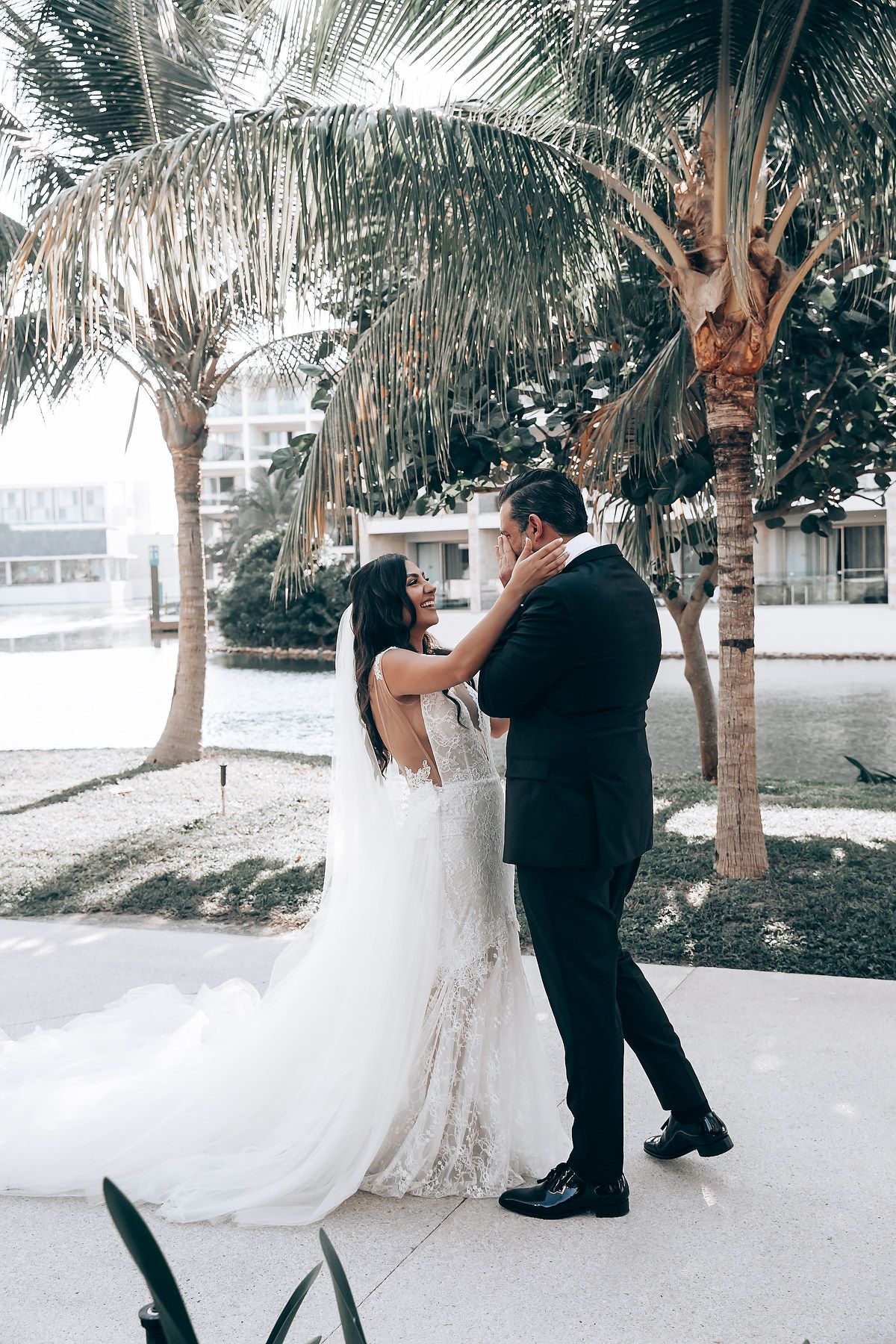 A romantic wedding moment under palm trees as a couple shares an intimate embrace in a tropical setting.