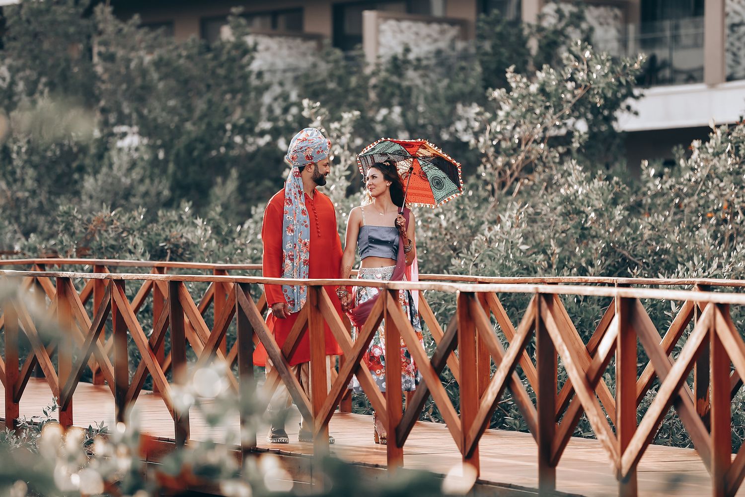 A wooden bridge walkway surrounded by blooming cherry blossom trees on a spring day.