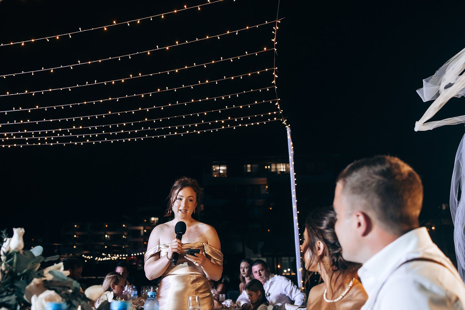 Wedding reception dance floor under string lights with guests celebrating at night.