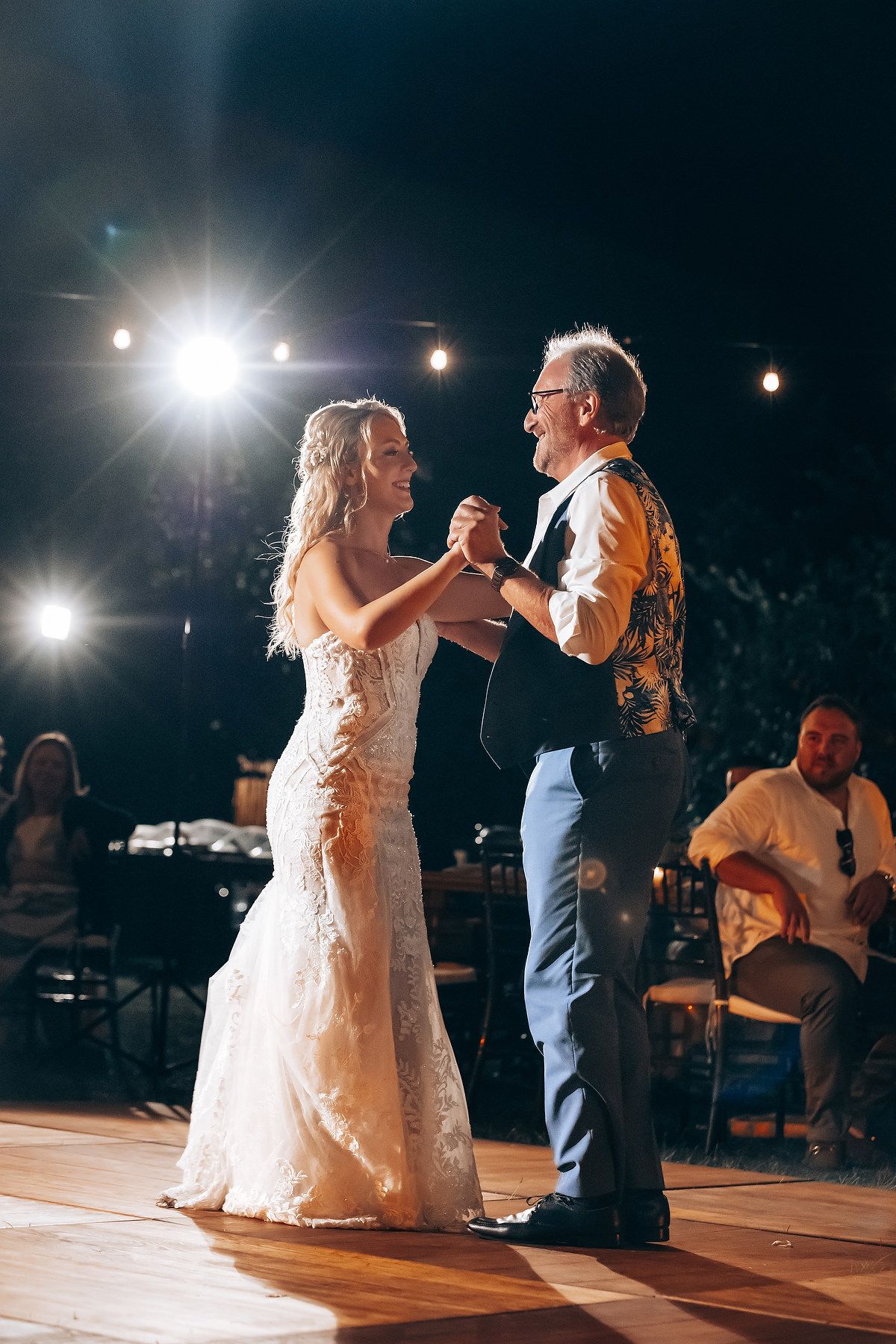 Wedding reception dance floor moments captured at night with spotlights illuminating the dancing couples.