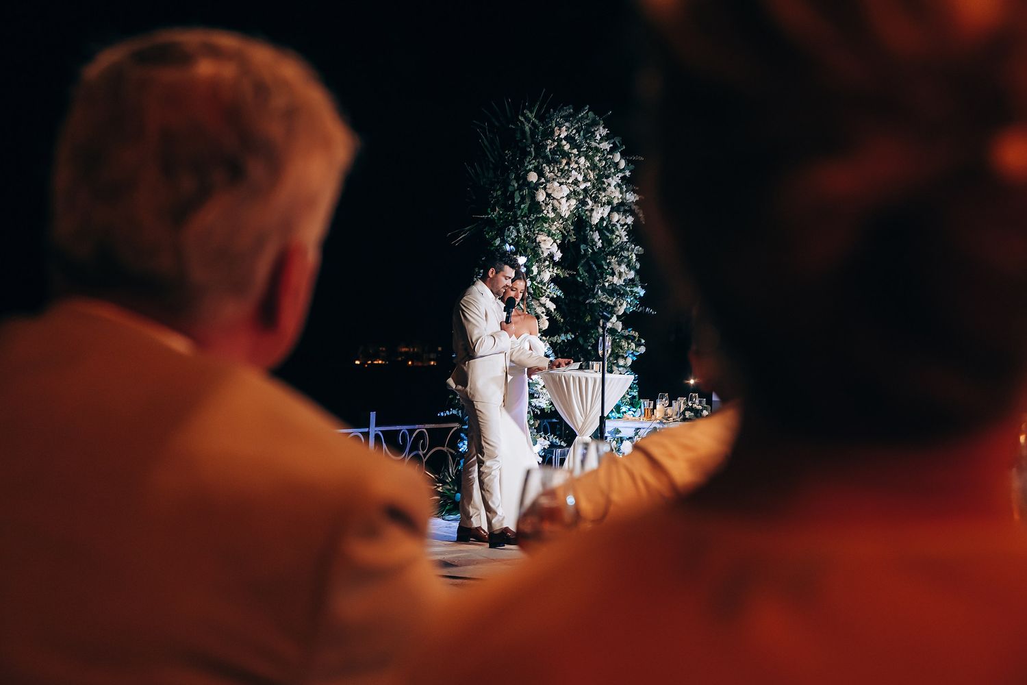 A couple in wedding attire dances together during their first dance at an evening reception.