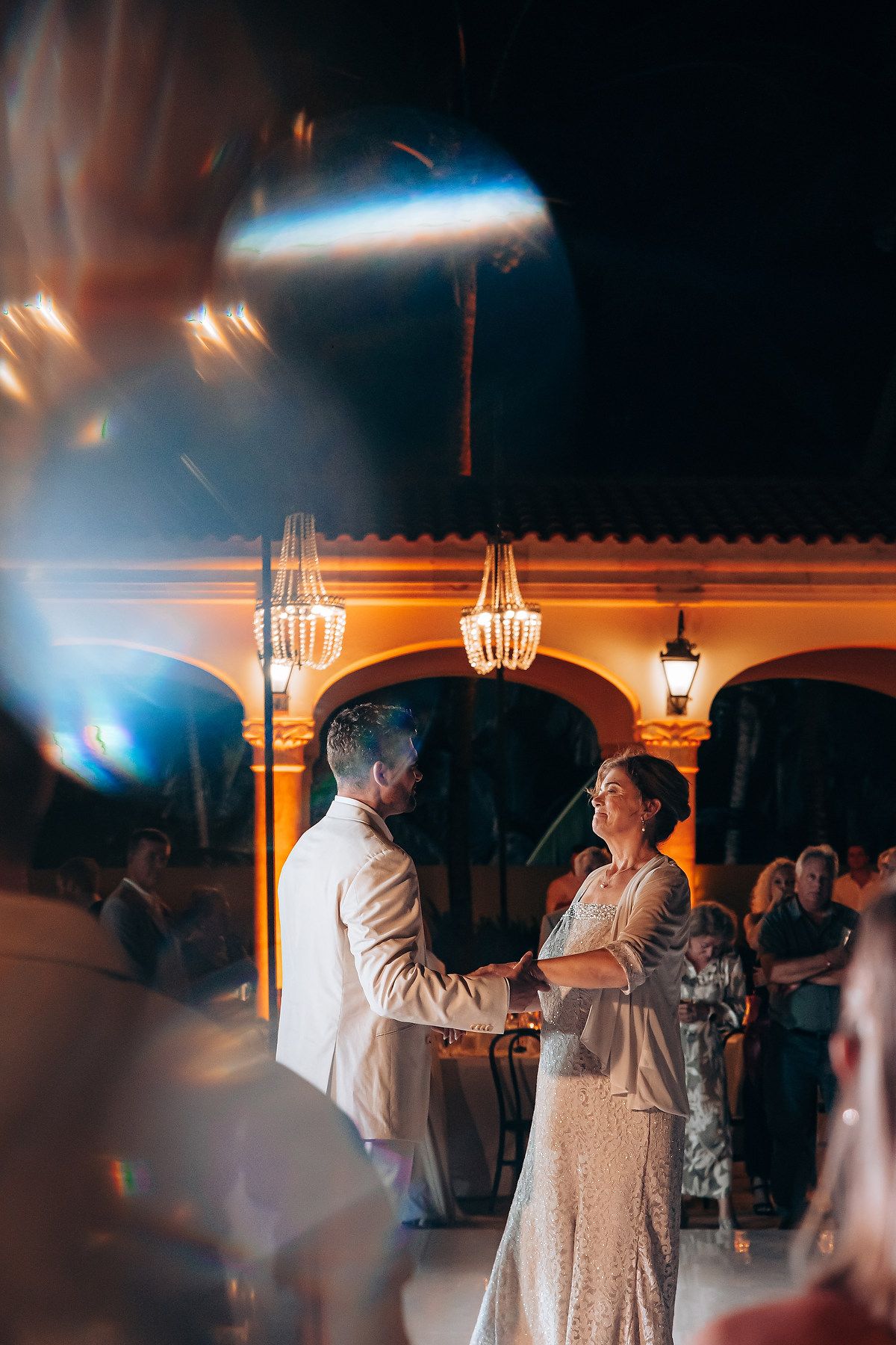 A tender dance moment captured at an evening wedding reception with glowing lanterns in the background.