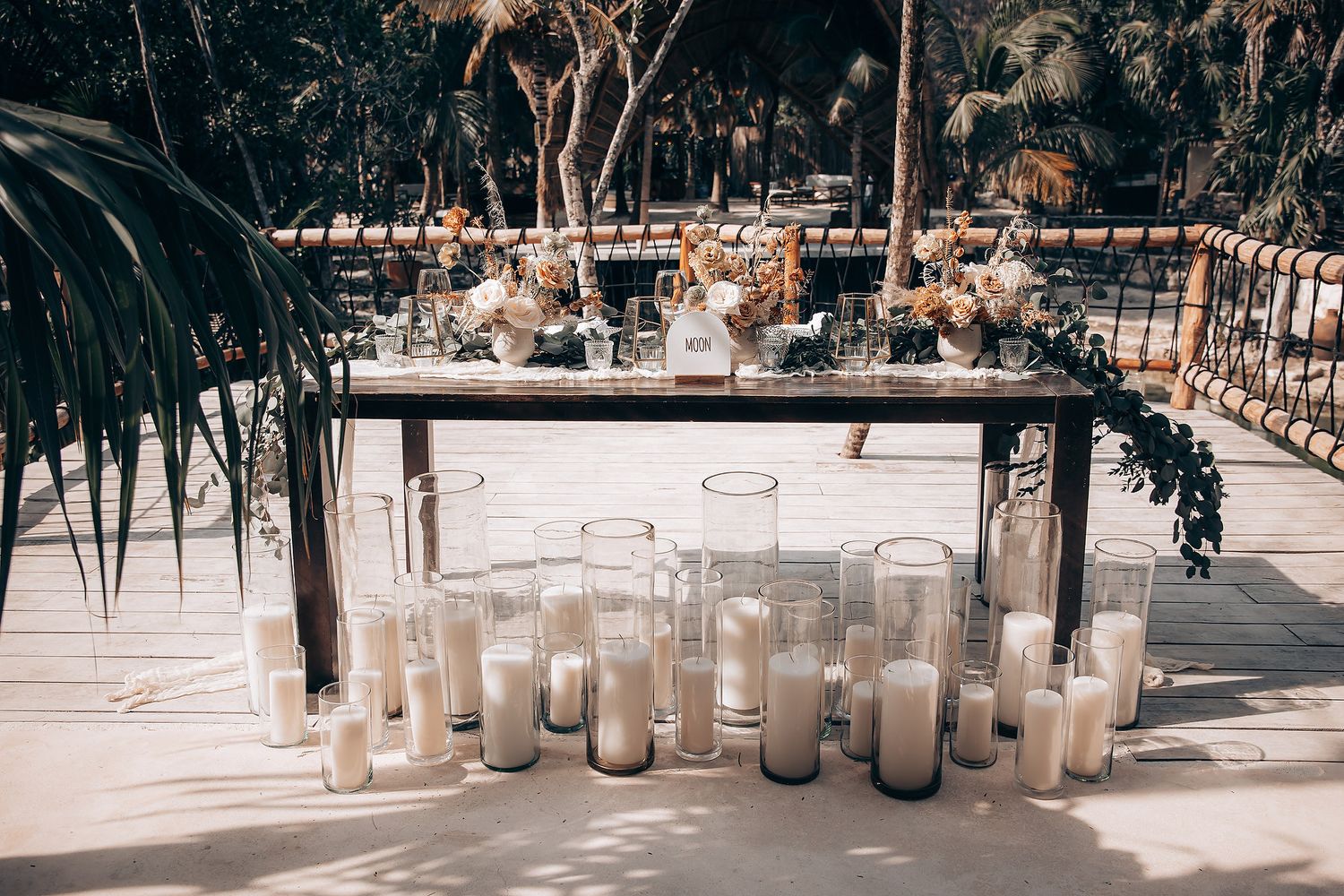 Row of glass lanterns with candles lining a rustic outdoor wedding venue pathway.