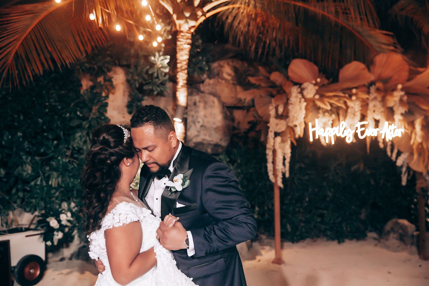 Romantic wedding dance under illuminated palm trees and fairy lights.