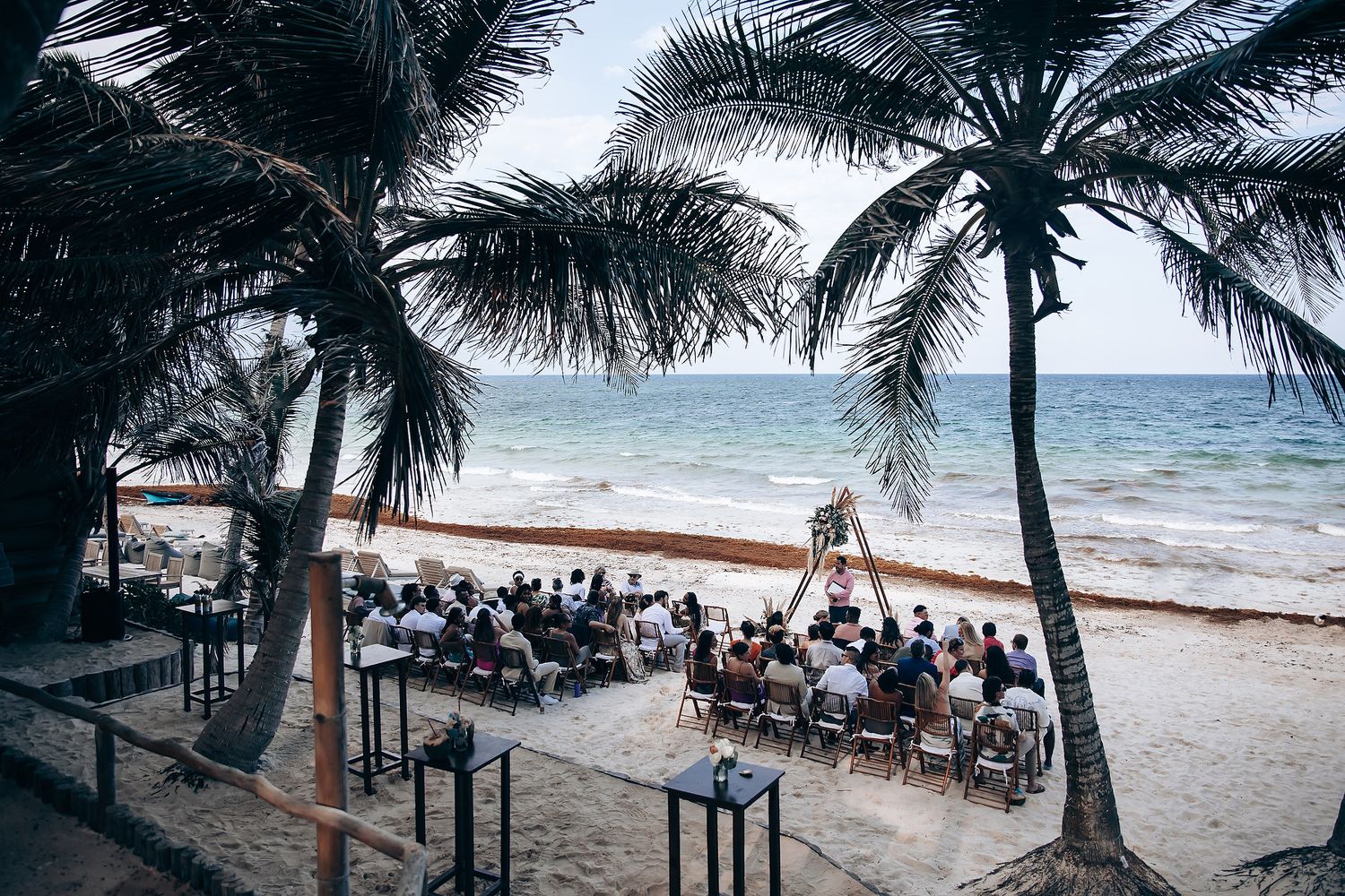 Beachfront wedding ceremony setup with palm trees and ocean views in a tropical setting.