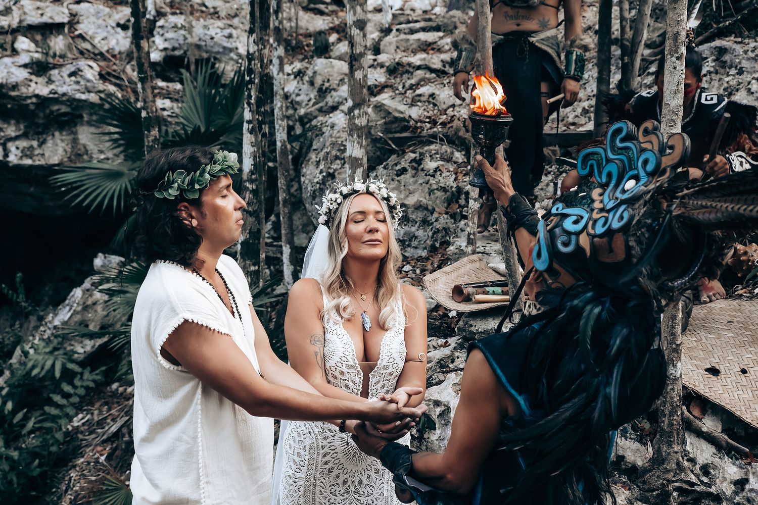 A couple in wedding attire poses for romantic photos against a rocky cliff backdrop.