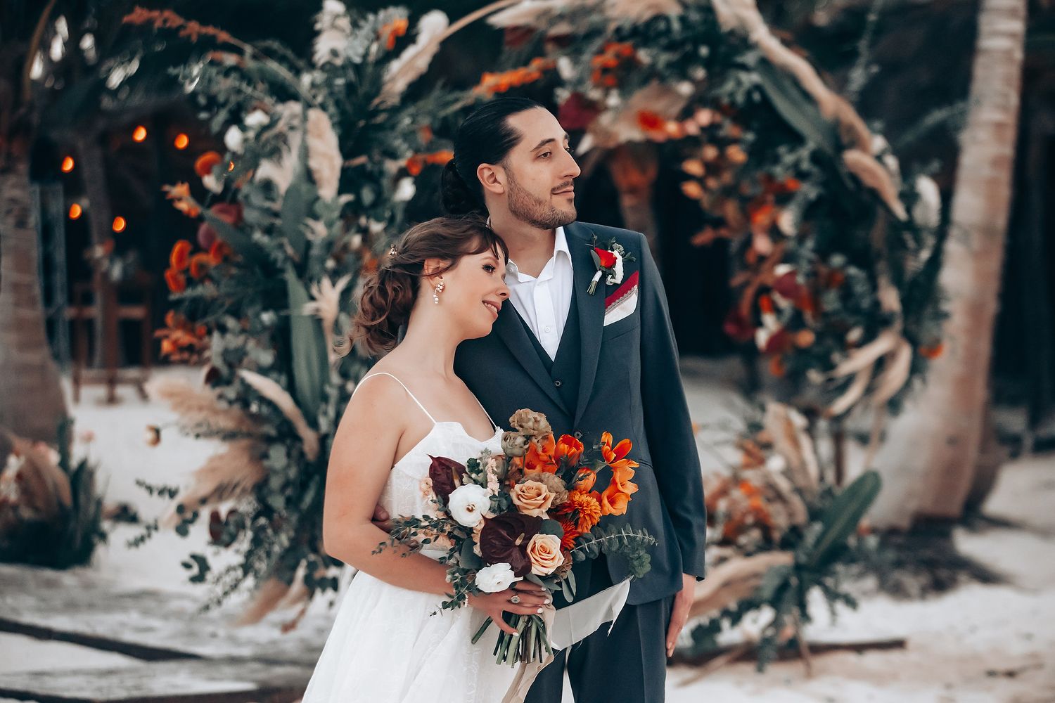 Wedding couple shares intimate moment among tropical decor and coral flowers.