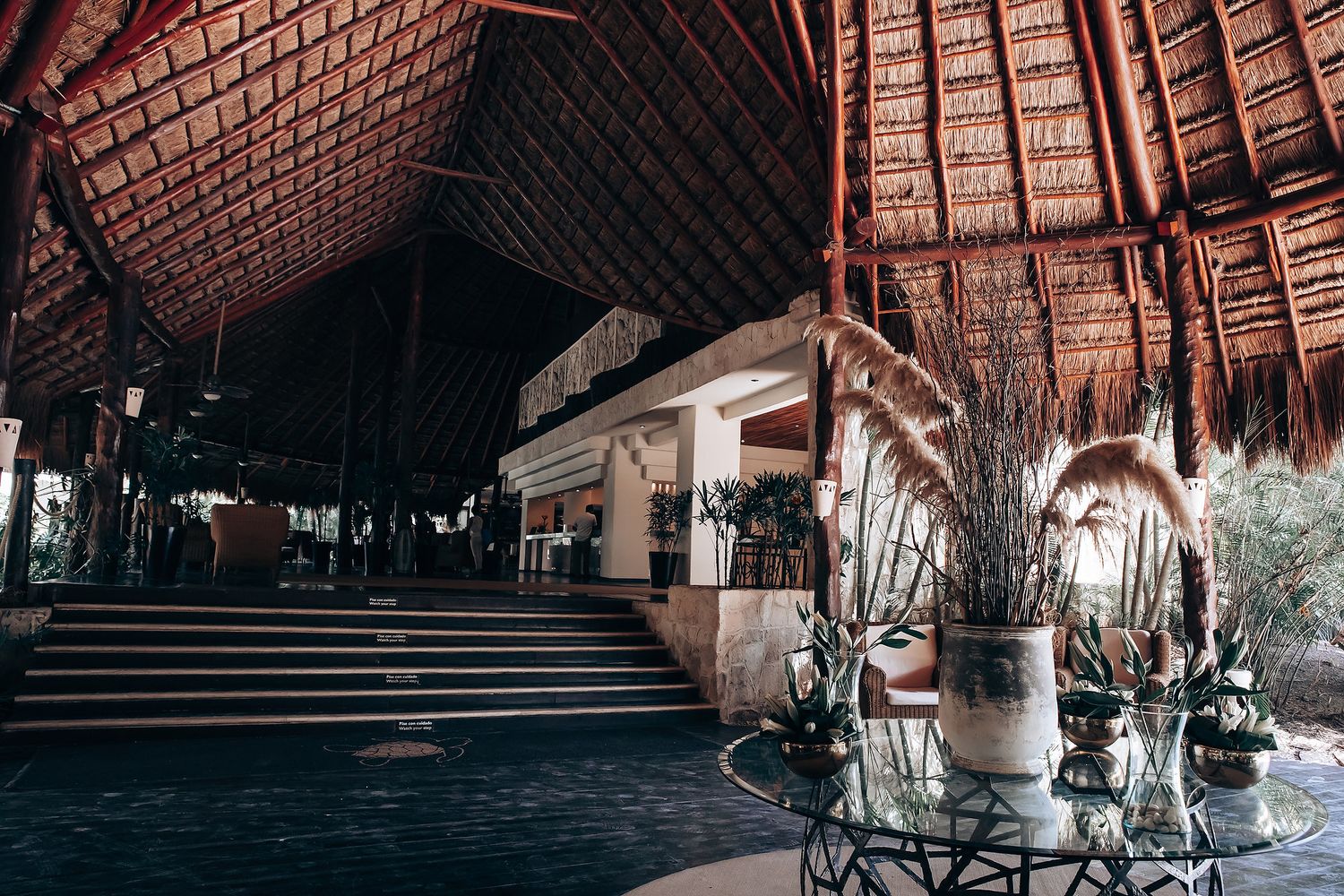 Architectural details of a rustic wooden resort with thatched roofs and natural surroundings in a tropical setting.
