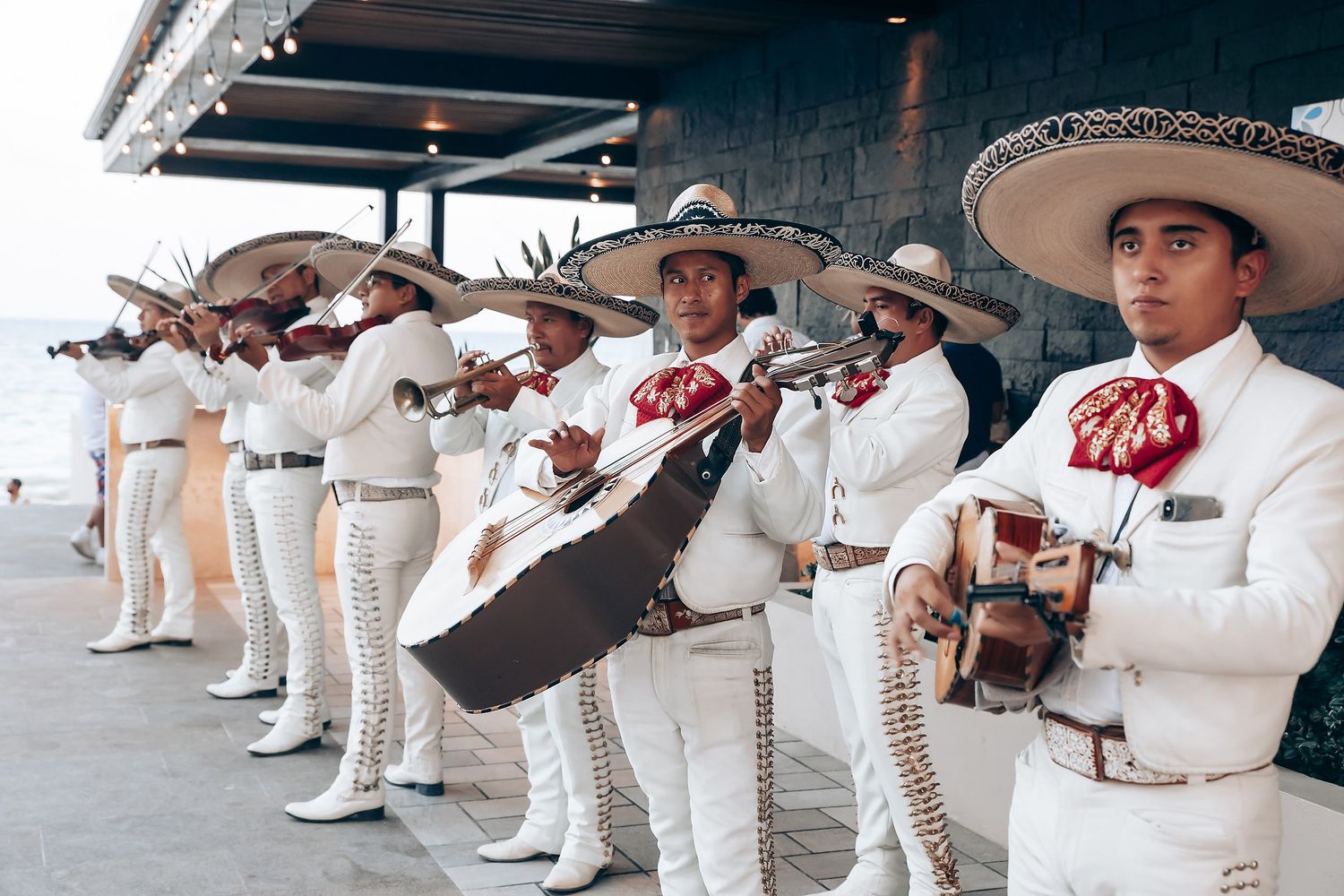 Traditional mariachi band in white uniforms and sombreros performing at an event.