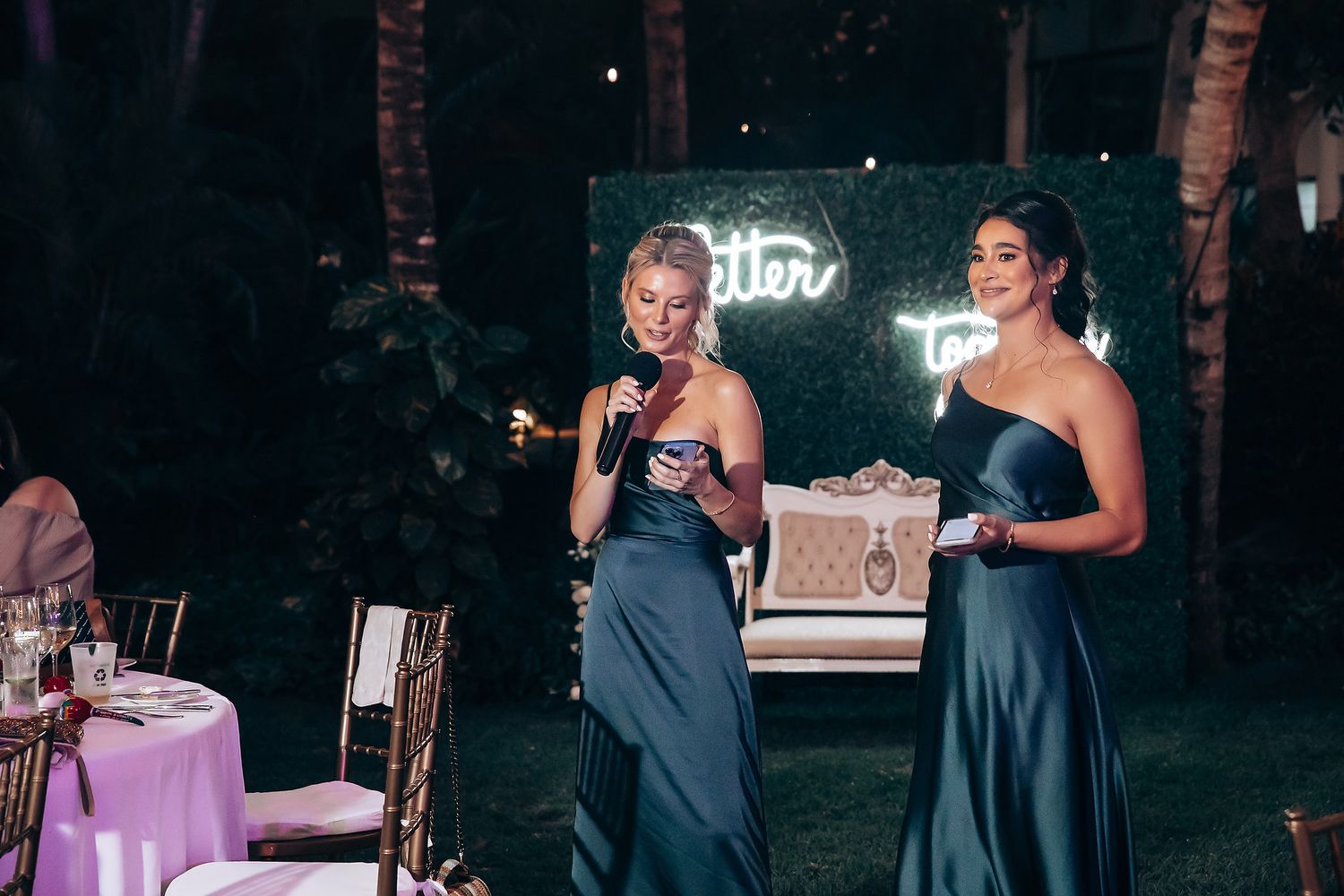 Outdoor wedding reception setup with string lights and rustic decor against a dark evening backdrop.