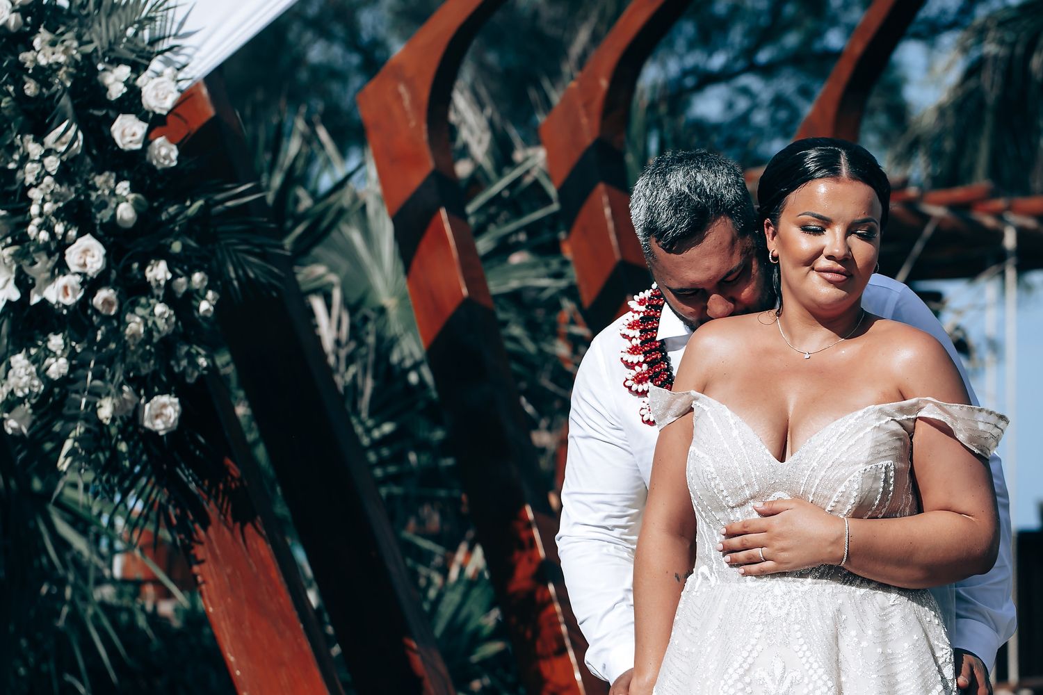 Wedding celebration under wooden beams decorated with red fabric and floral arrangements.