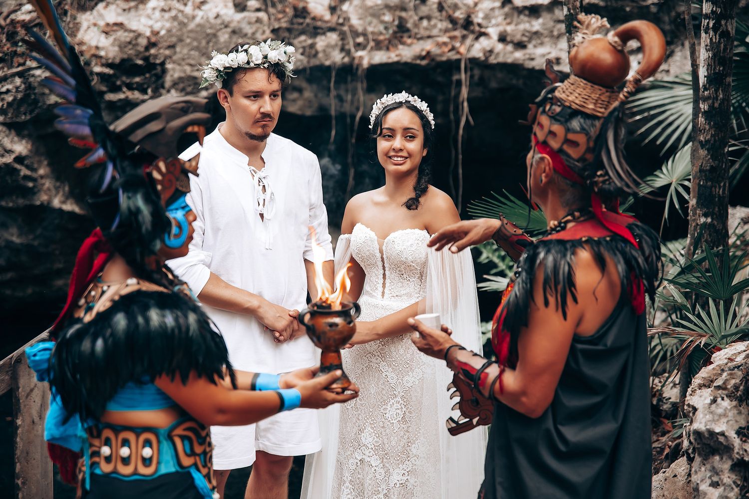 Traditional Mayan ceremony participants perform rituals with ceremonial objects in a natural cave setting.