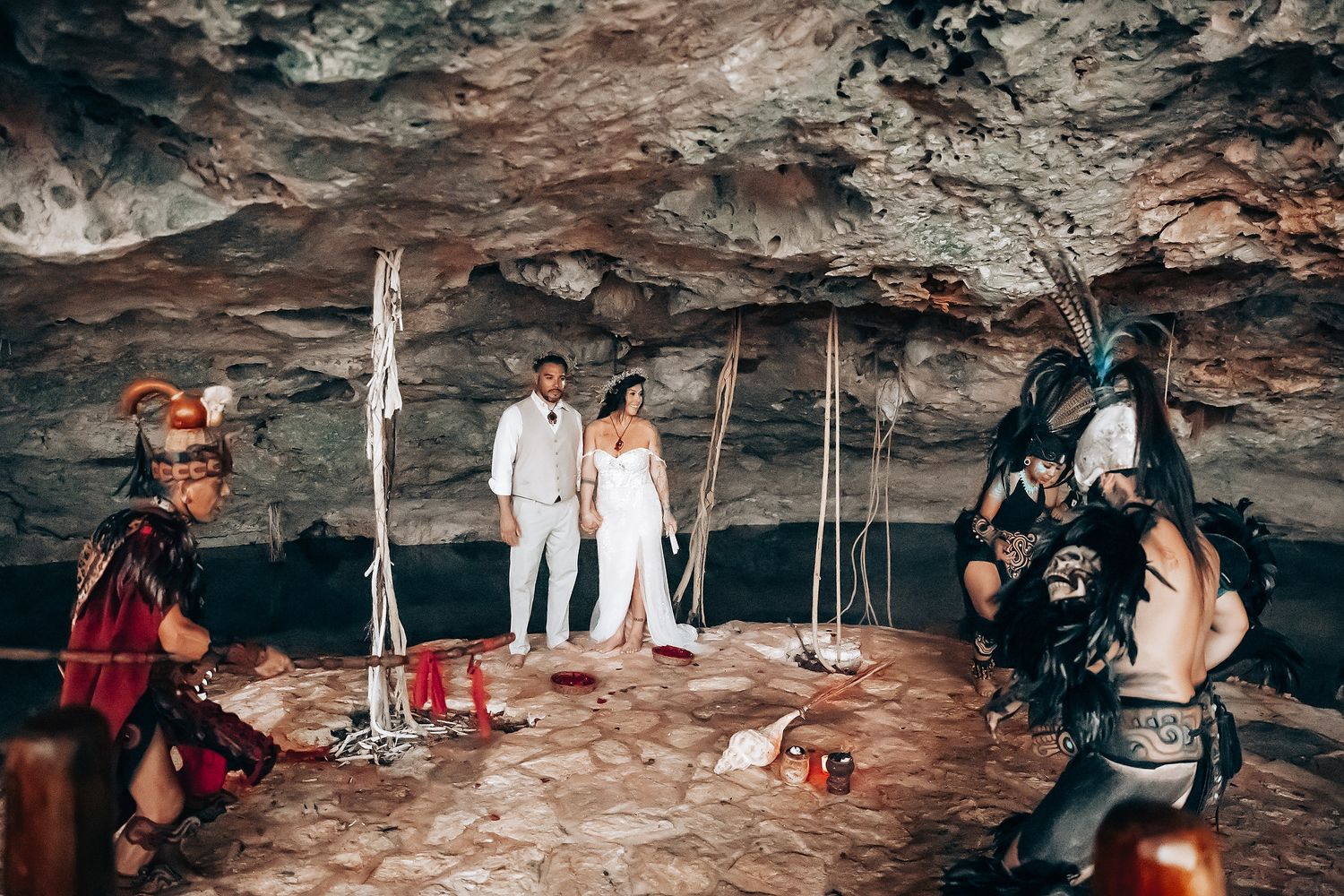 Wedding ceremony participants gather inside a dramatic cave setting.