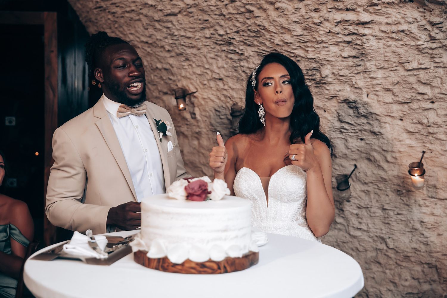 Newlyweds share a moment while cutting their white wedding cake at their reception.